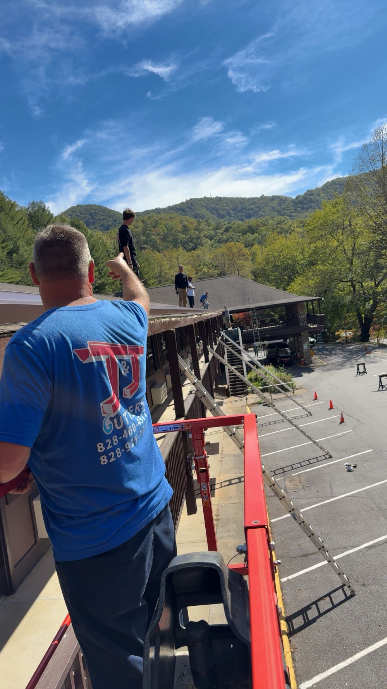 A person taking a photo of people on a rooftop with a mountainous landscape and blue sky in the background.