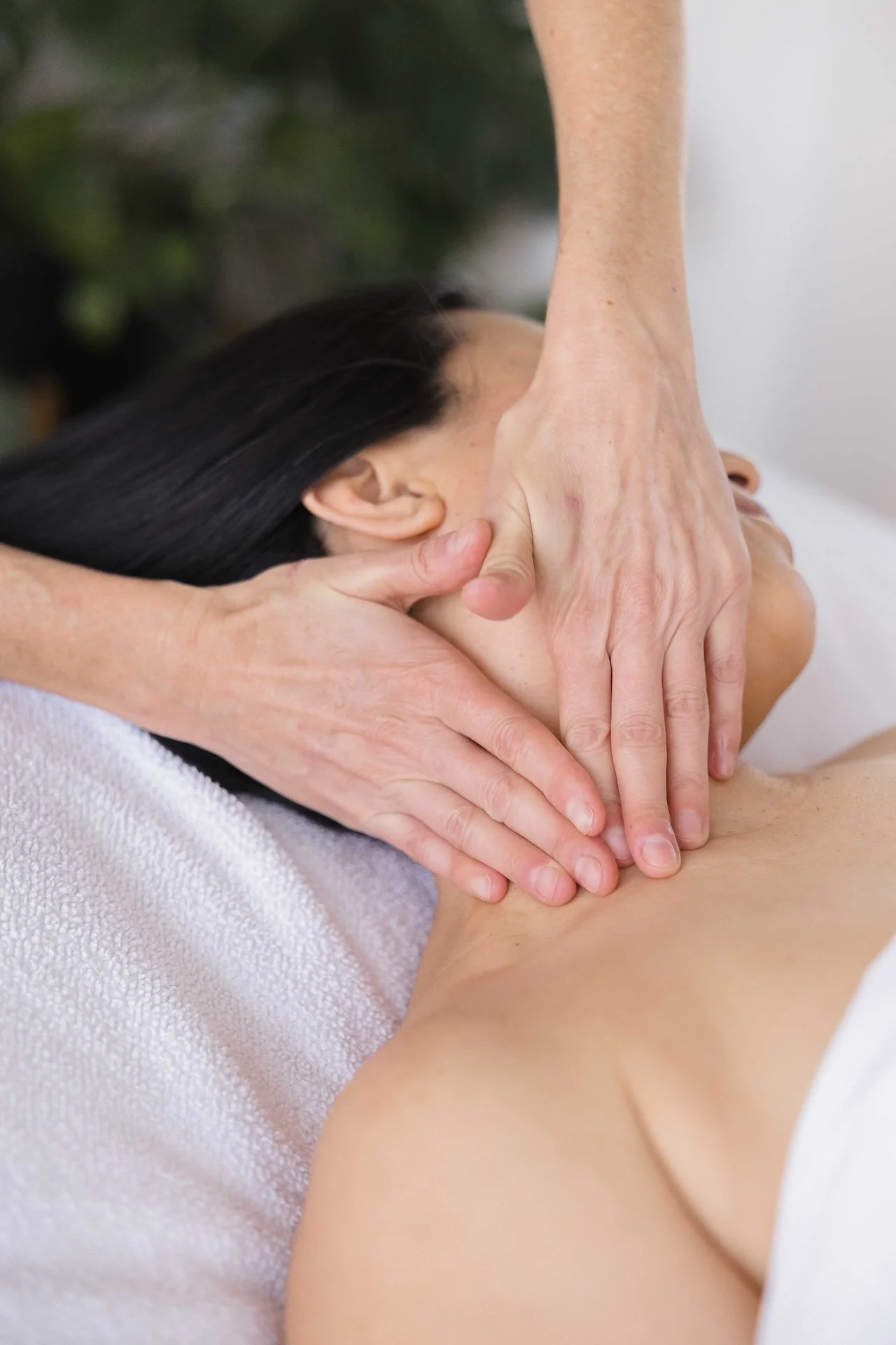 Close-up of a person receiving a massage, with focus on the neck and hand of the massage therapist.