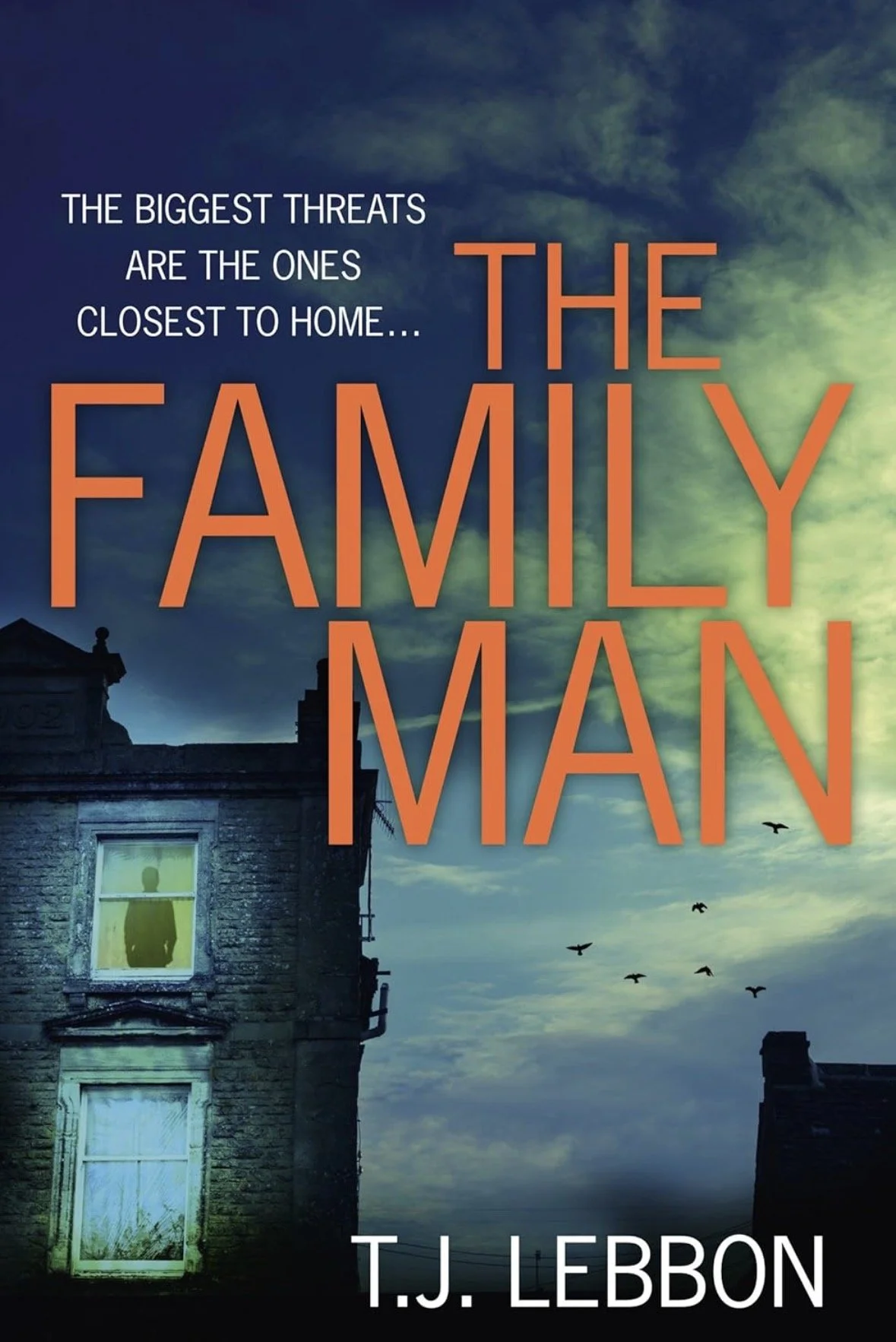 Book cover featuring a dark, cloudy sky with birds flying, and an old house with a window showing a silhouette of a person. The title reads 'The Family Man' by T.J. Lebbon, with a subtitle about threats being close to home.