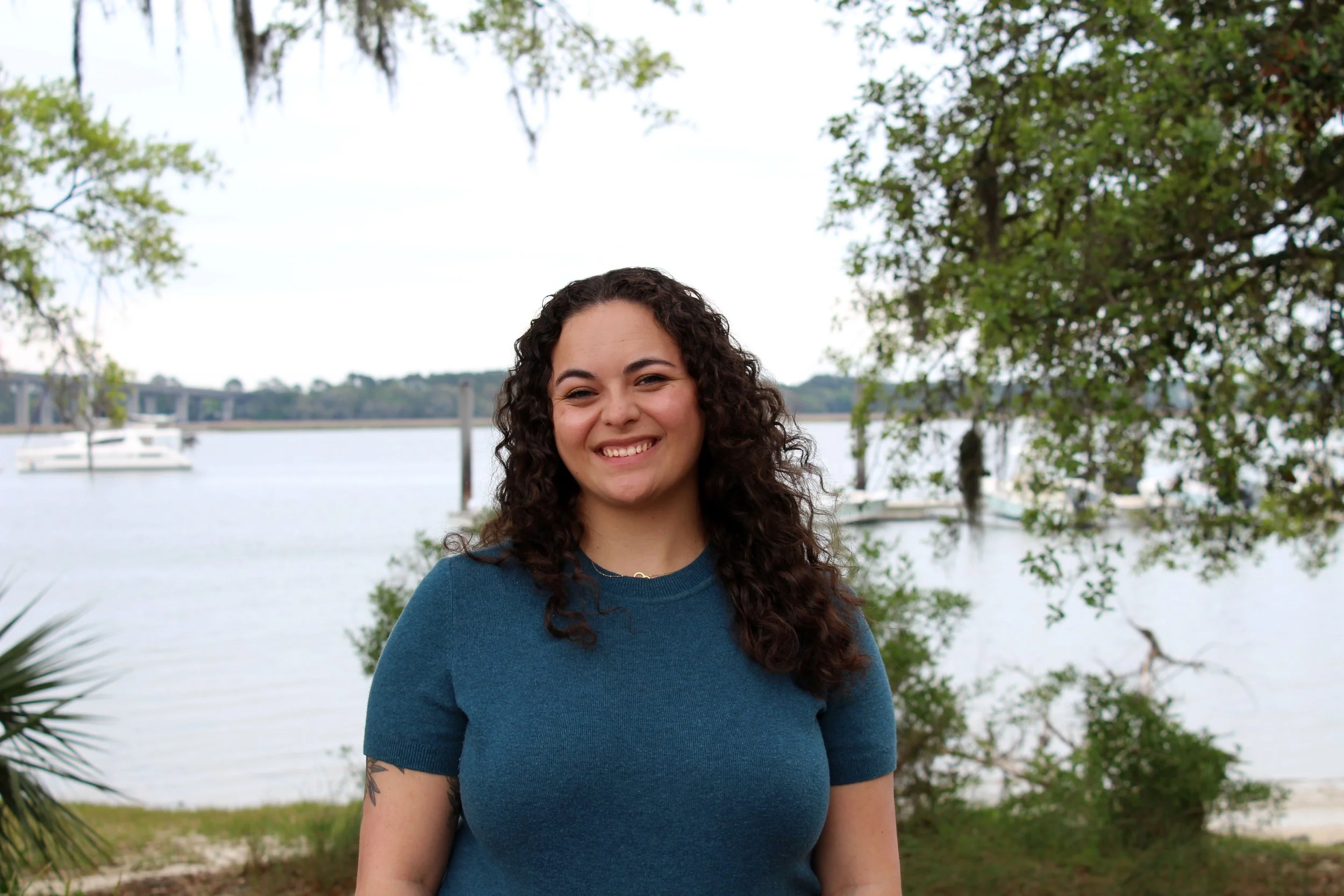 Natalie Wan (Bruss) Smiling at the camera in front of Charleston waterfront.