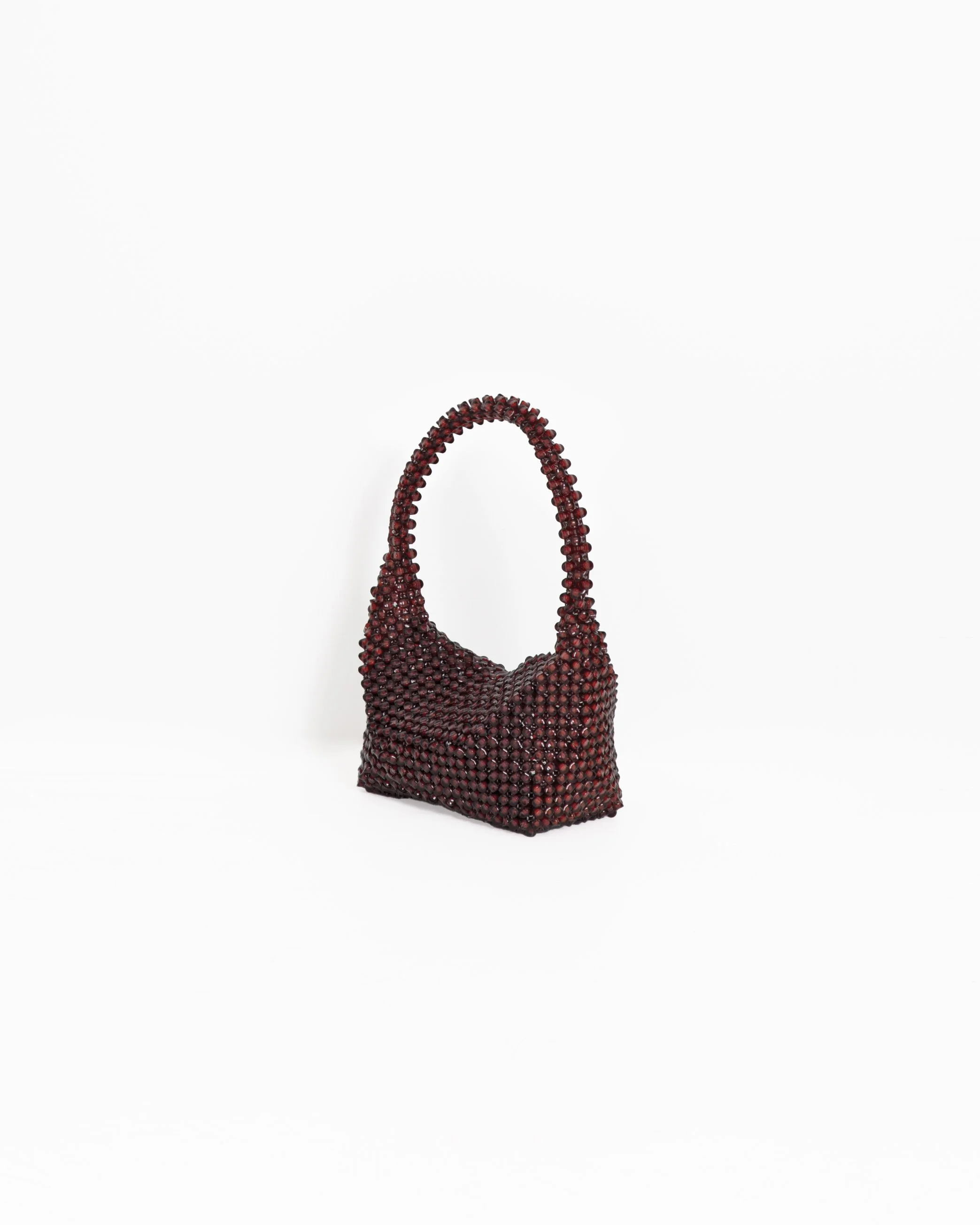 A handbag covered in small, dark red beads, set against a plain white background.