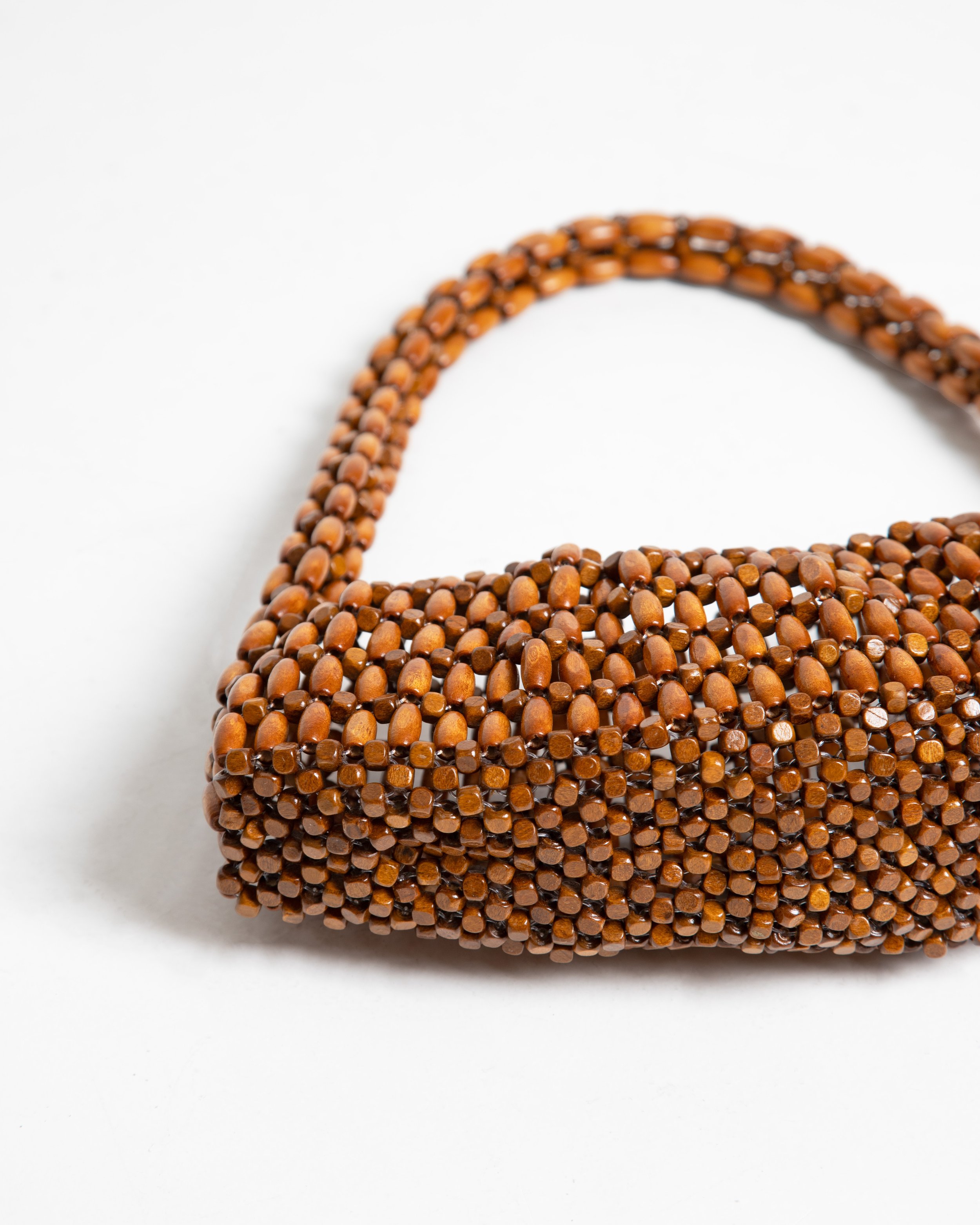 Brown beaded handbag with a curved handle on a white background.