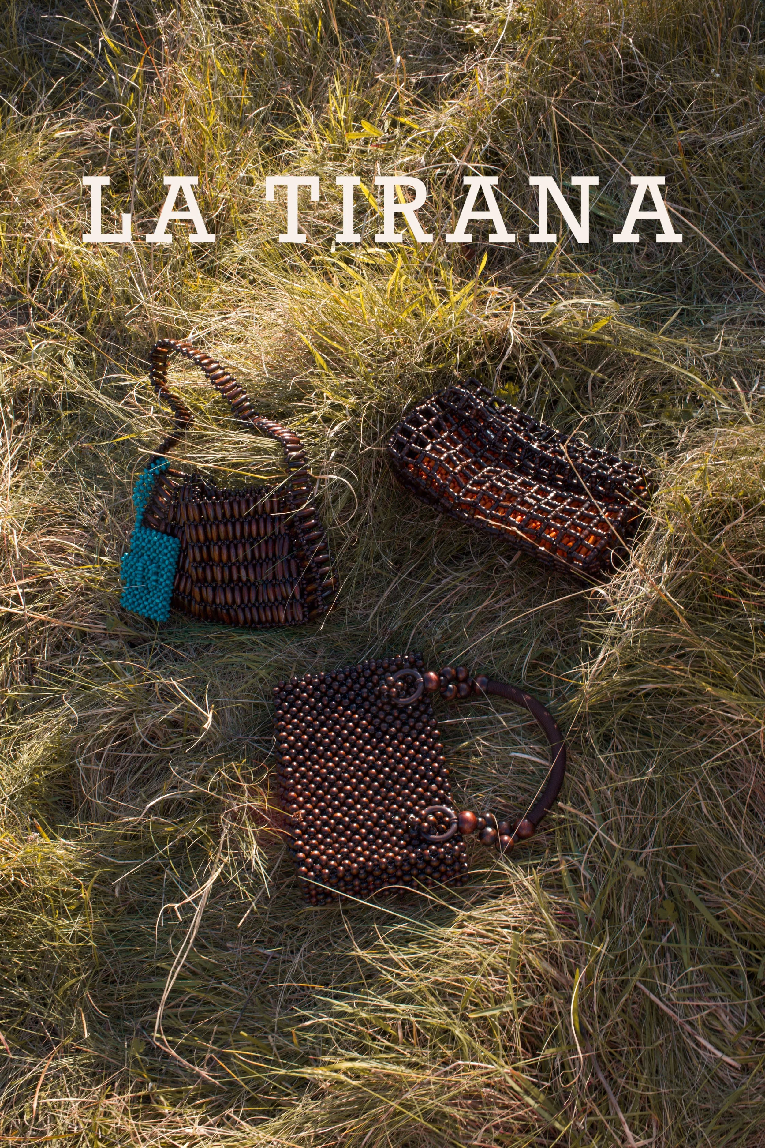 Set of beaded handbags and purses placed on grassy terrain with the text 'LA TIRANA' overlaid.
