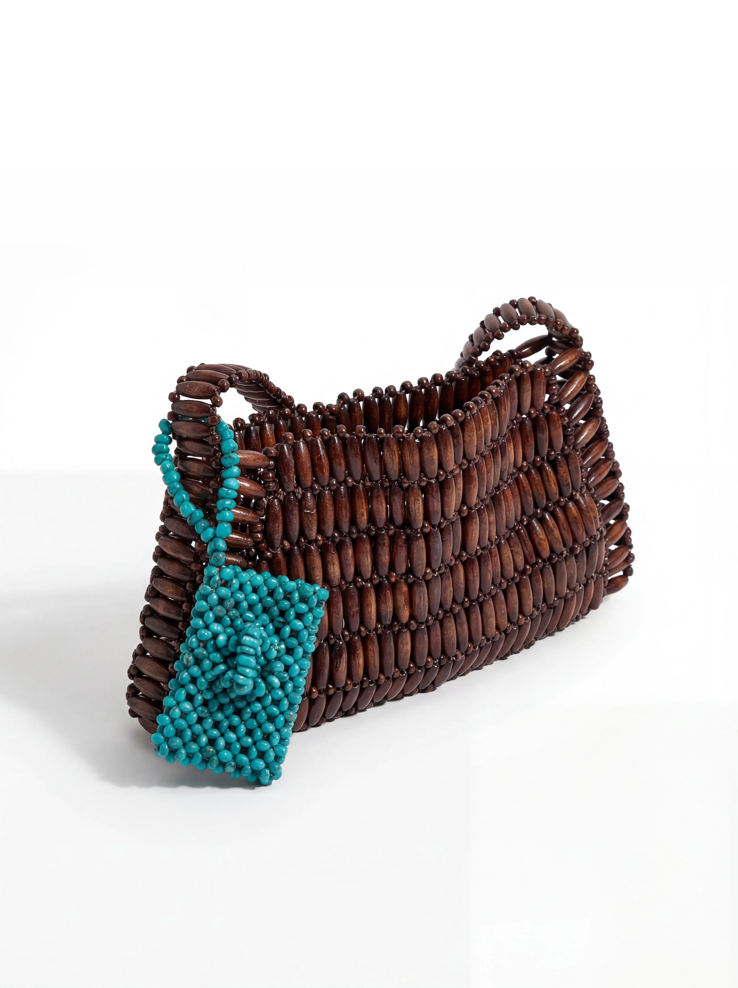 A handbag made of dark brown beads with two rounded handles, accented with a turquoise beaded drawstring pouch hanging from one handle, set against a plain white background.