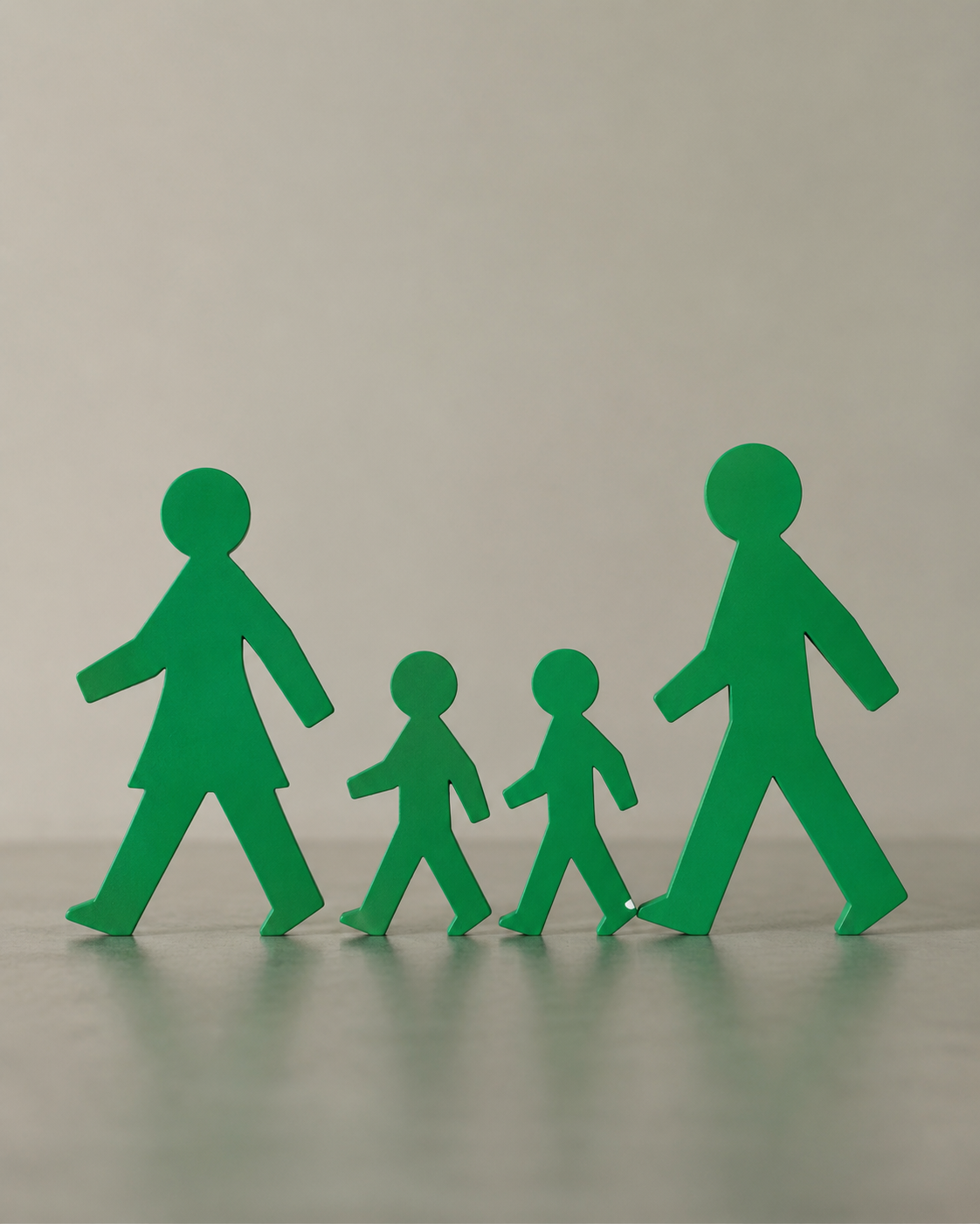 Green paper cutouts of a family with two children and two adults walking together.