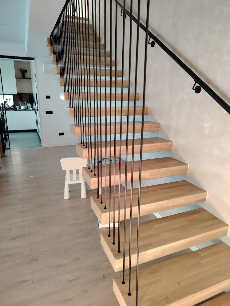 Modern staircase with wooden steps and black metal railing in a contemporary home interior.