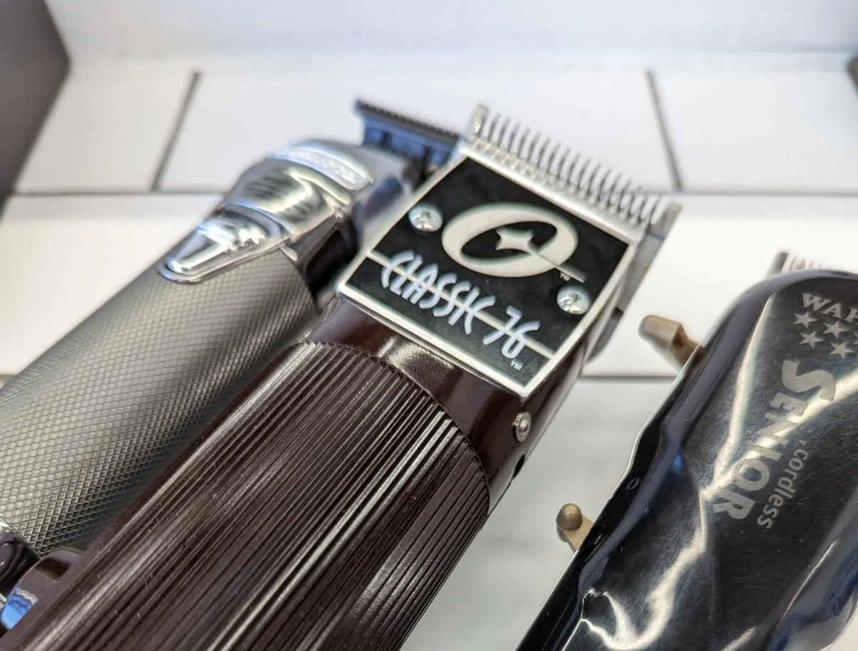 Close-up of vintage barber clippers with labels saying 'Classic 76' and 'Wahl Super Shaver'.