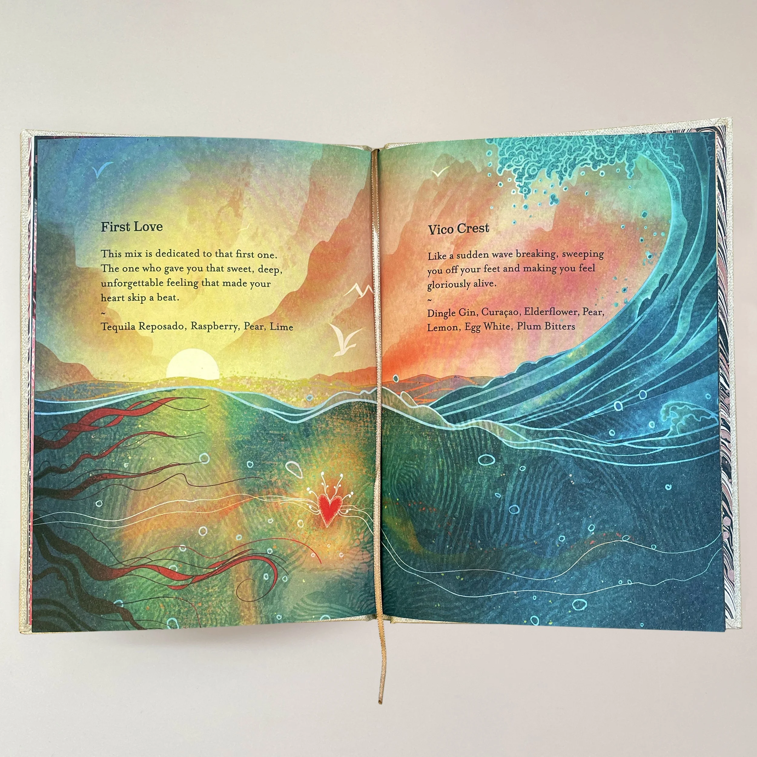 An open colorful art journal spread with watercolor backgrounds in shades of yellow, pink, orange, blue, and green. The left page has the title "First Love" with a short paragraph about it, and the right page titled "Vico Crest" with a description. T