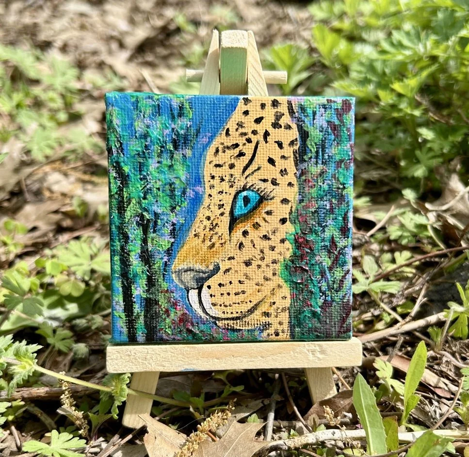 Luna the Leopard with turquoise eyes in a beautiful flower and tree