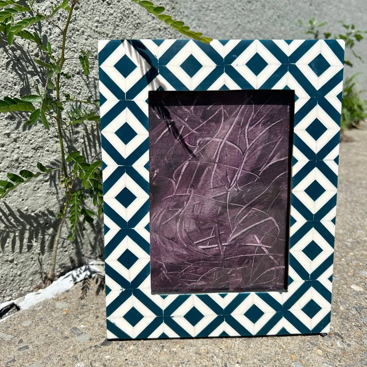 Abstract painting by Heather Collis eggplant in color called Unraveled framed in a blue and white tile tabletop frame.