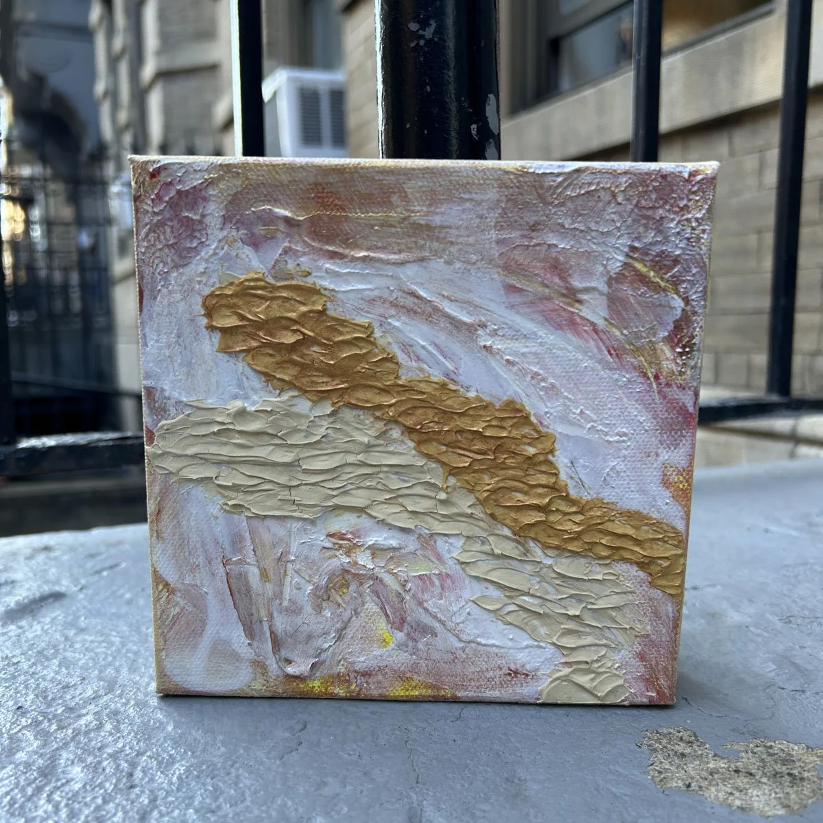 A 6x6 gallery canvas showing the Road to Nowhere abstract painting outdoors in natural light, displayed on a low stone ledge.