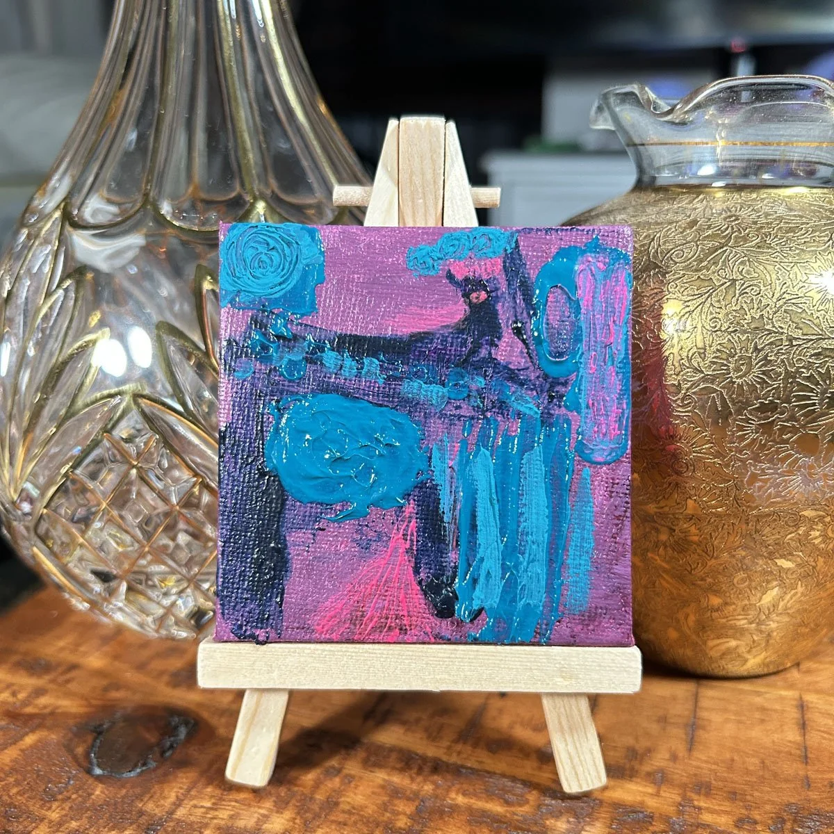 Heather Collis original mini painting, abstract goat themed art with textured teal and dark blue impasto paint on a purple and pink background, displayed on a small wooden easel.