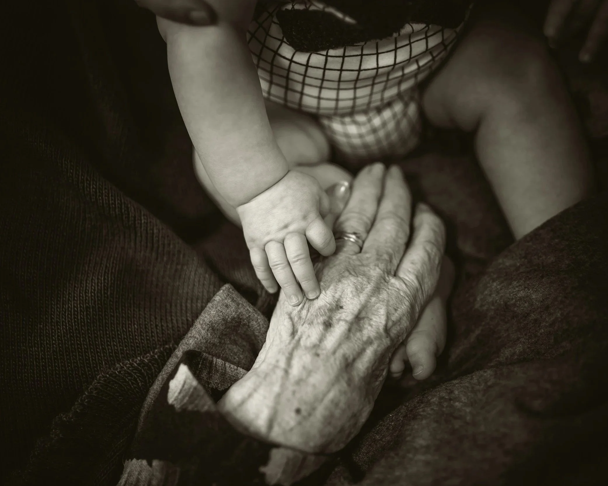 A child's hand gently resting on an elderly person's hand, showing a moment of connection and tenderness.