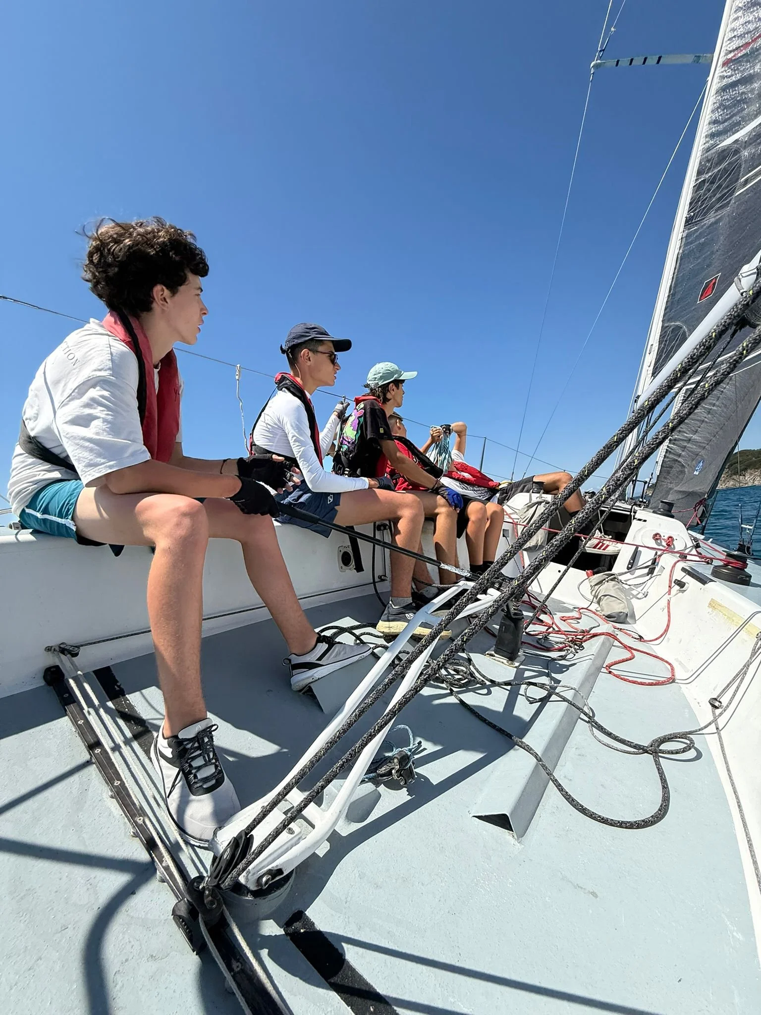 Gruppo di ragazzi che fanno vela su una barca in mare con il cielo sereno.