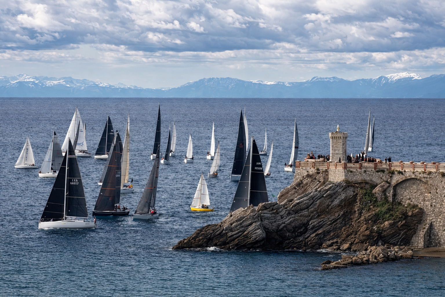 Barche a vela in mare vicino a un promontorio con torre e pubblico, con montagne innevate sullo sfondo.