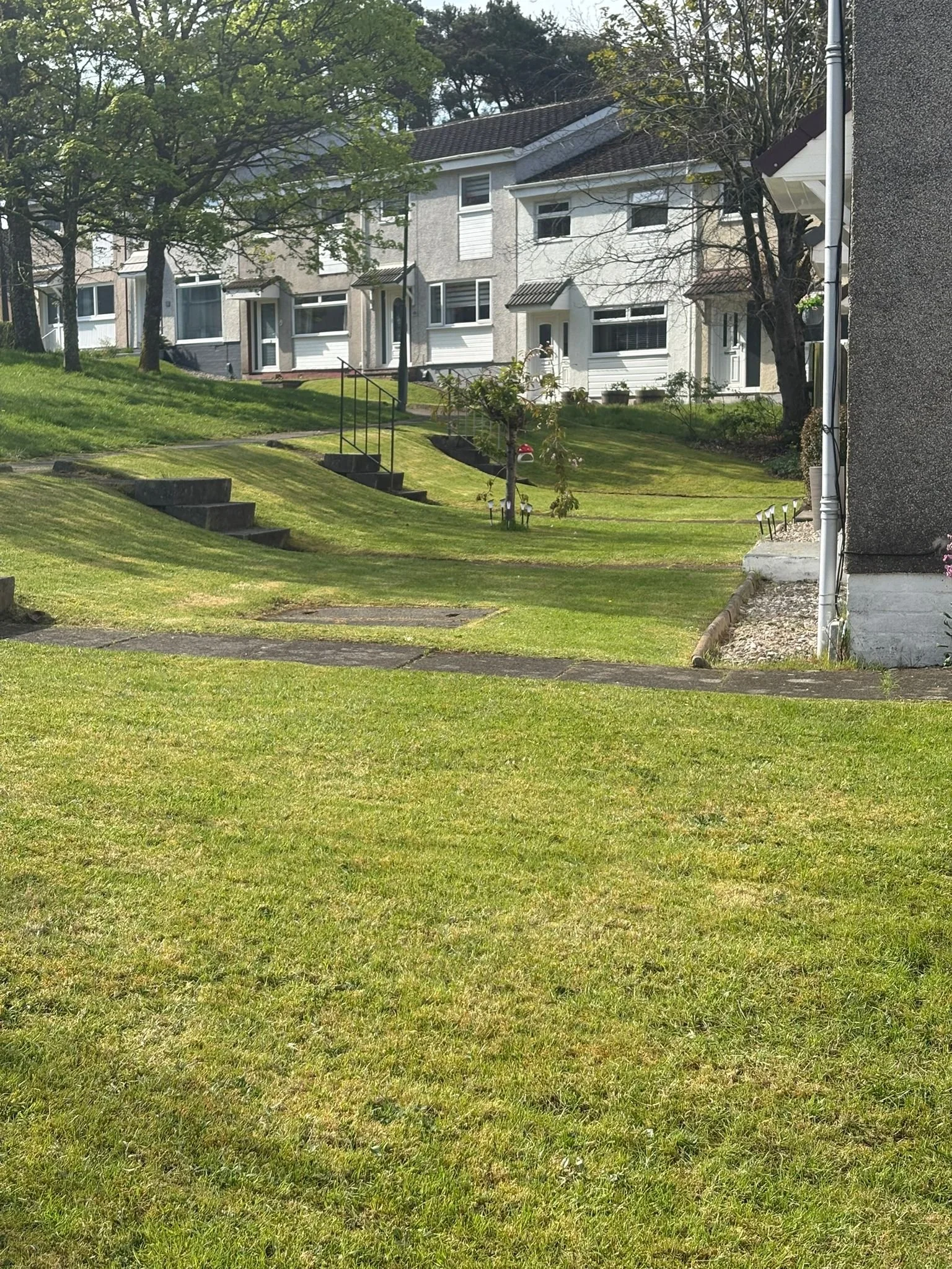 Red and white house on a hill with a grassy front yard and trees in the background.