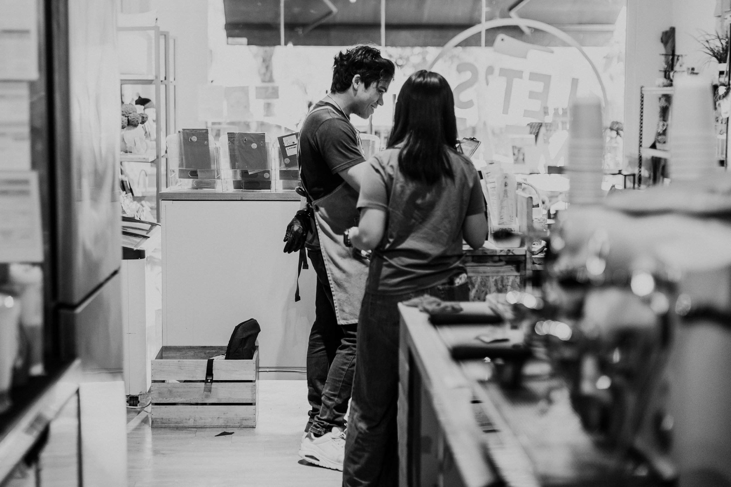 Two people, a man and a woman, are shopping together in a store, standing at a checkout counter and engaging in conversation.