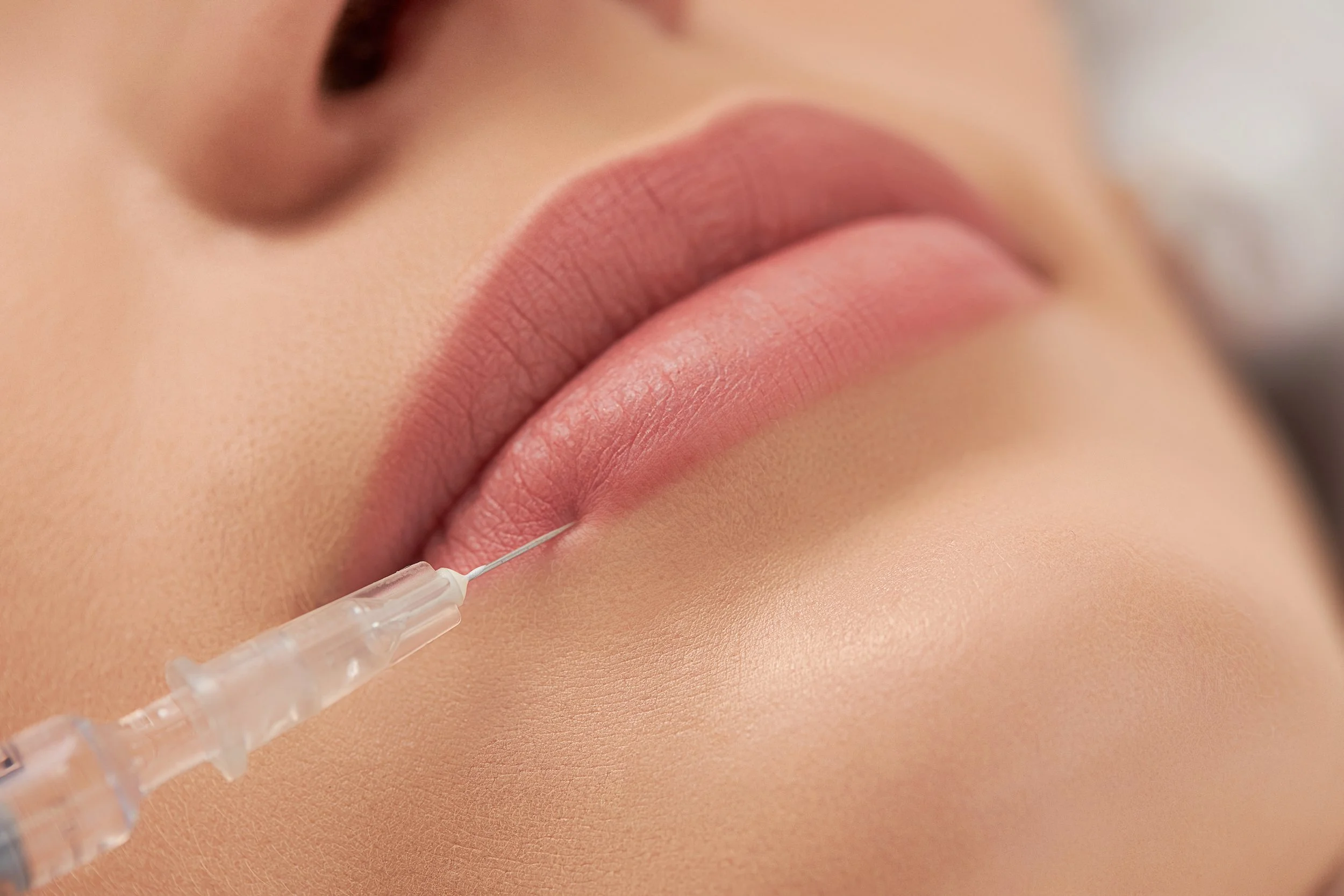 Nahaufnahme eines Lippenstifts und eines Medikationsinjektionsstifts, die auf die Haut einer Hautpartie gerichtet sind.