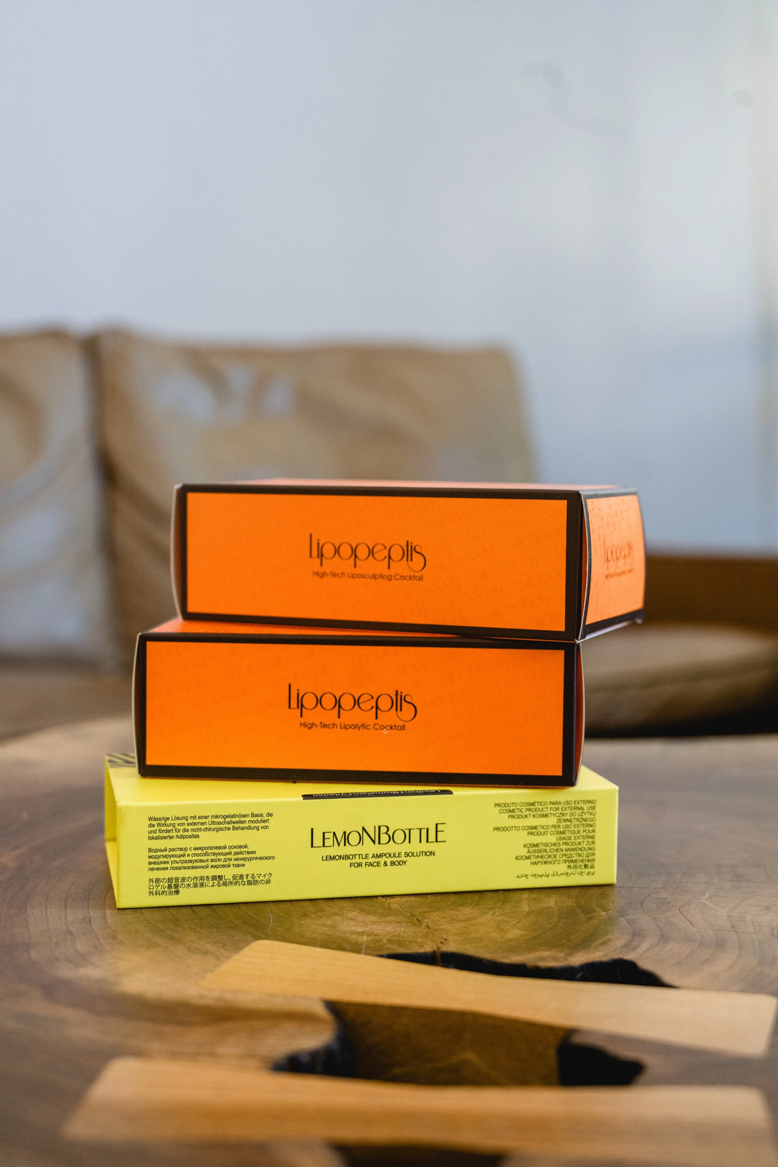 Drei farbige Boxen auf einem Tisch, von oben betrachtet, mit Produktenamen "Lipopeptis" und "Lemon Bottle".