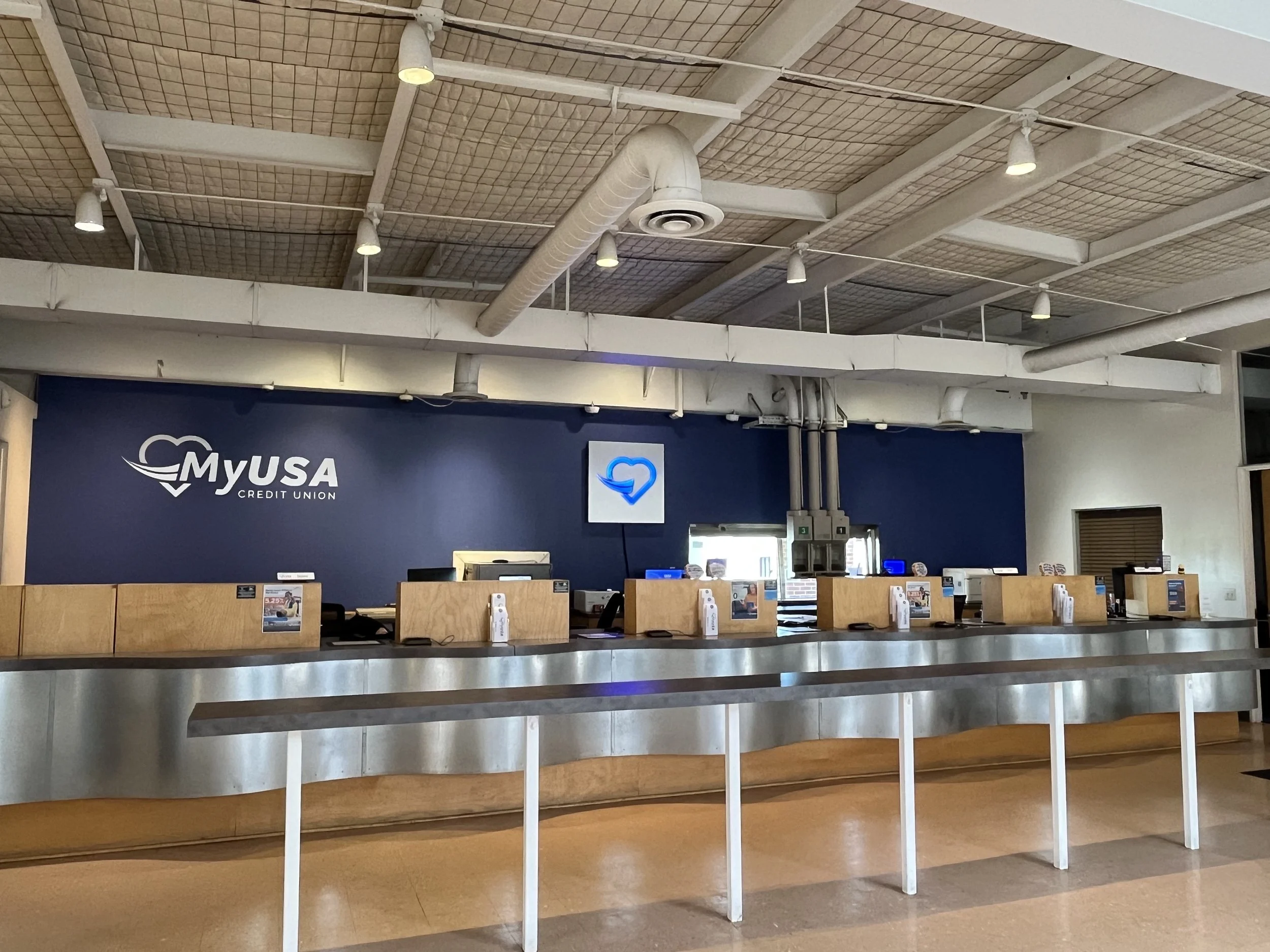 Empty service counter at MyUSA credit union with a blue wall, desks, and a beaming heart logo