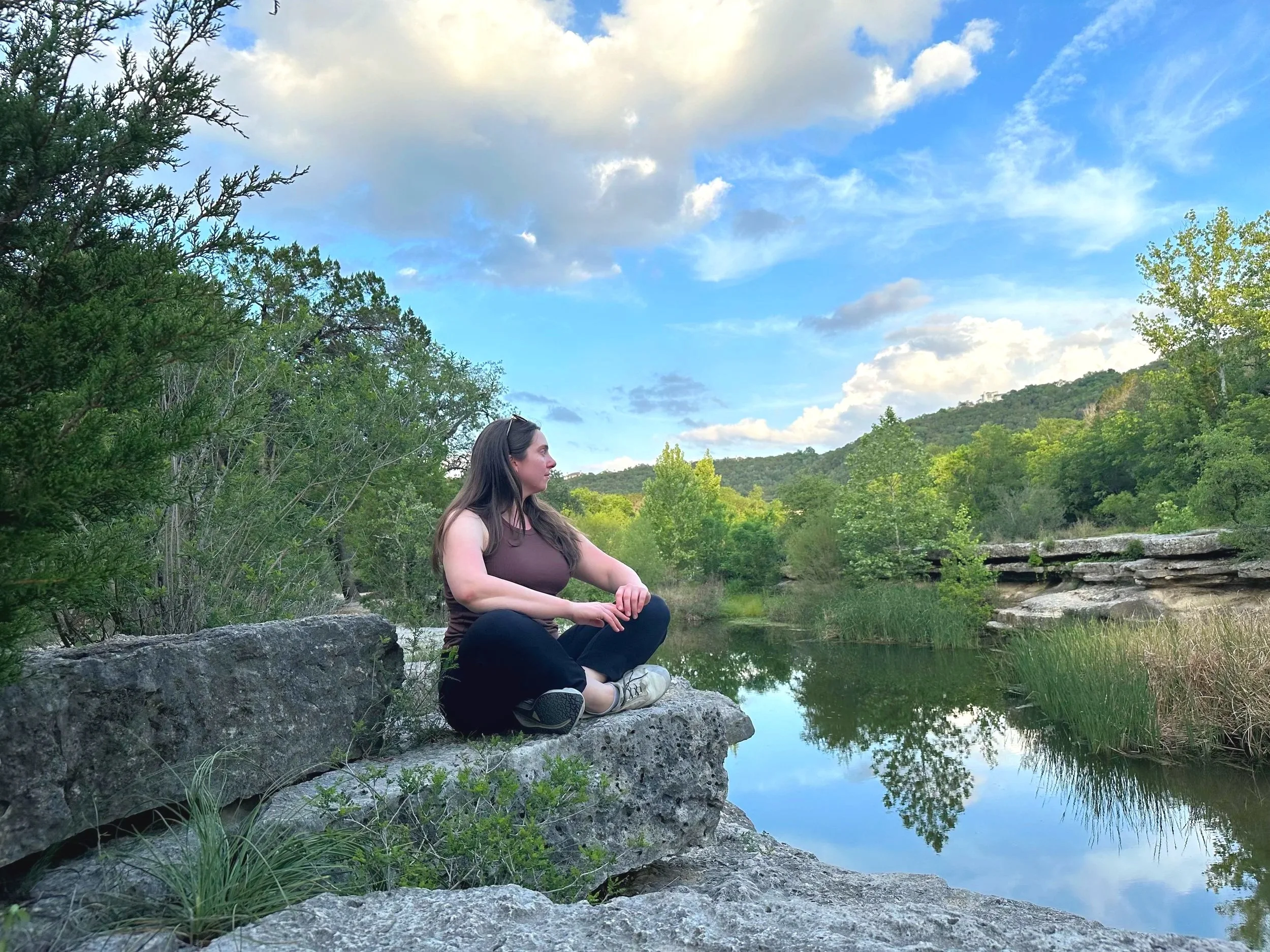 Austin Texas dietitian in meditation pose practicing mindfulness in nature at Bull Creek near Westlake Hills ATX while building private practice for nutrition therapy