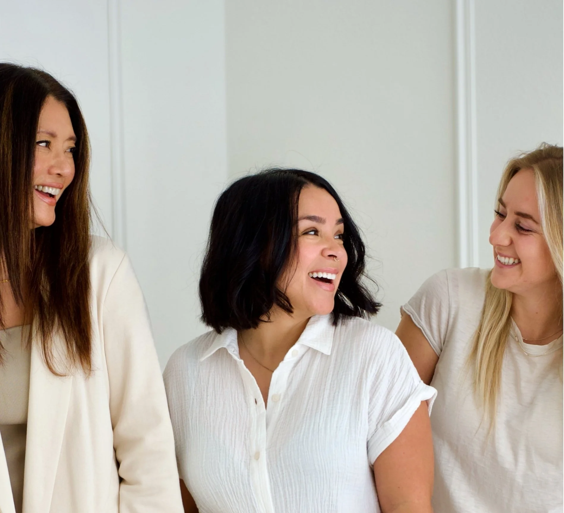 Meredith Cashman and her therapy team in Angora Hills, smiling and talking in a bright room with plain light-colored walls.