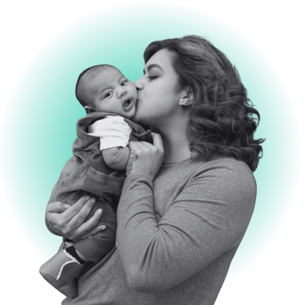 A black and white photo of a woman holding a young child and kissing his cheek, against a circular gradient teal background.