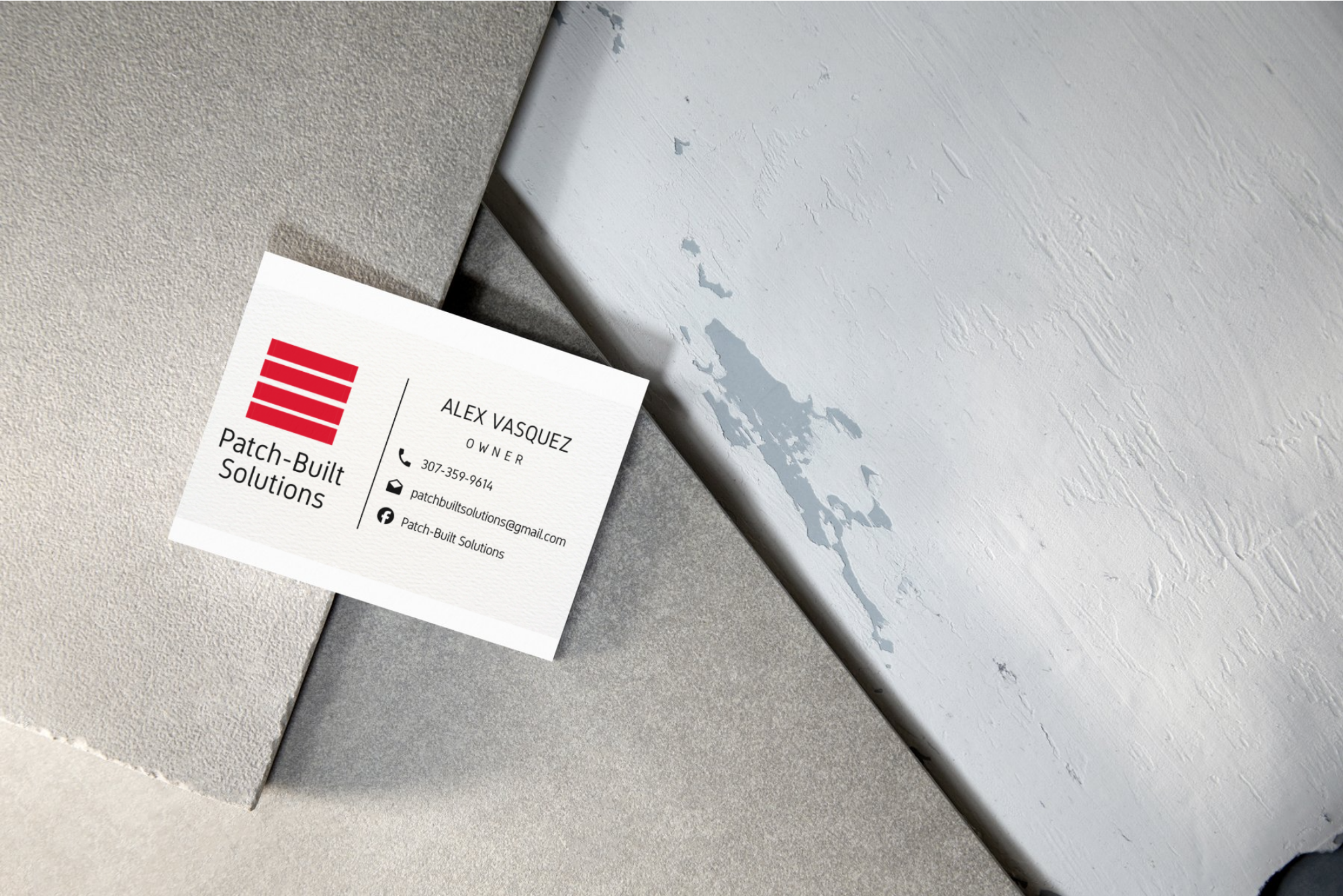 Business card for Patch-Built Solutions on a textured ceiling surface with peeling paint.