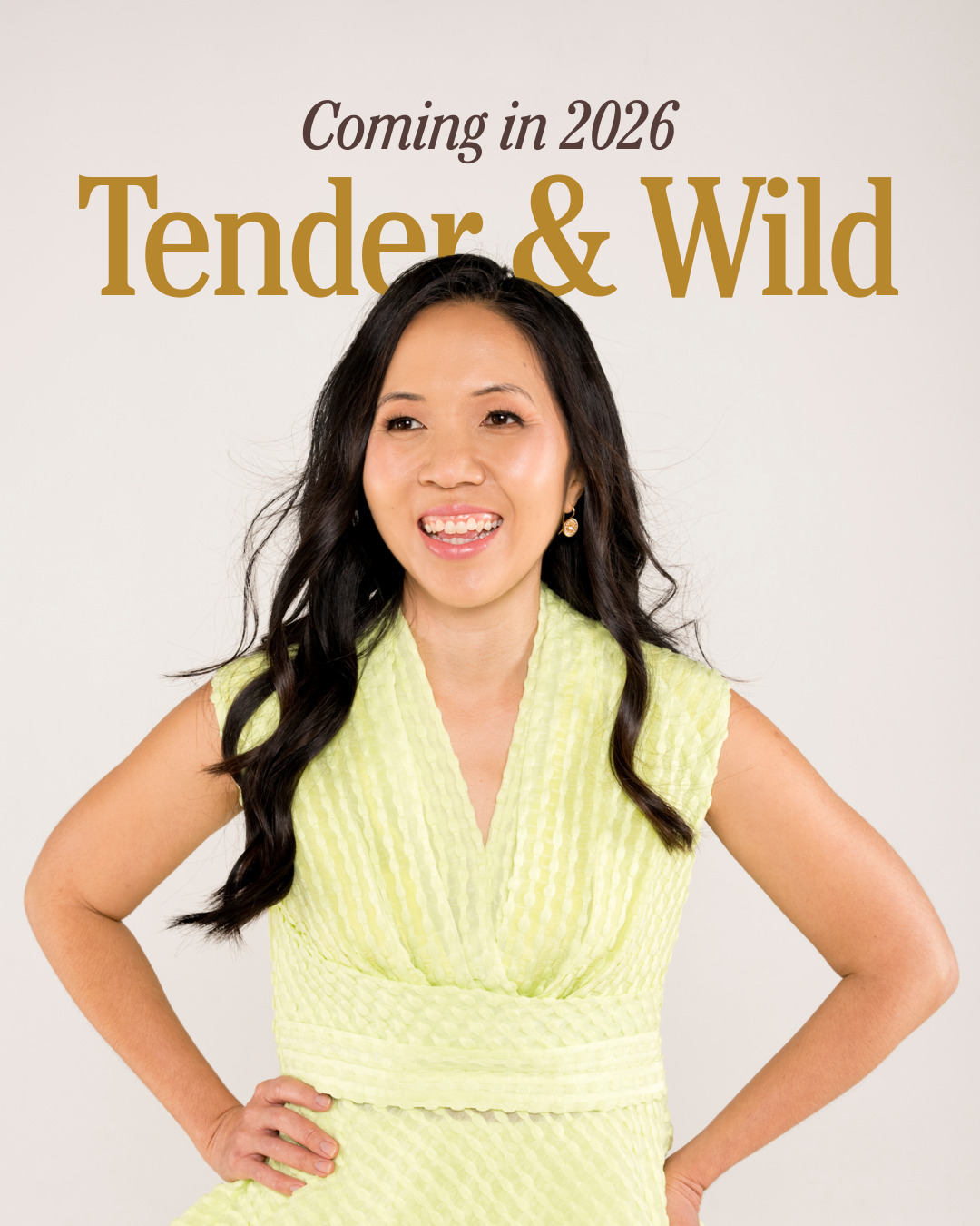 A woman with long dark hair, smiling and wearing a yellow textured sleeveless dress, posing with her hand on her hip against a plain light background. Text overlay says "Coming in 2026" and "Tender & Wild".