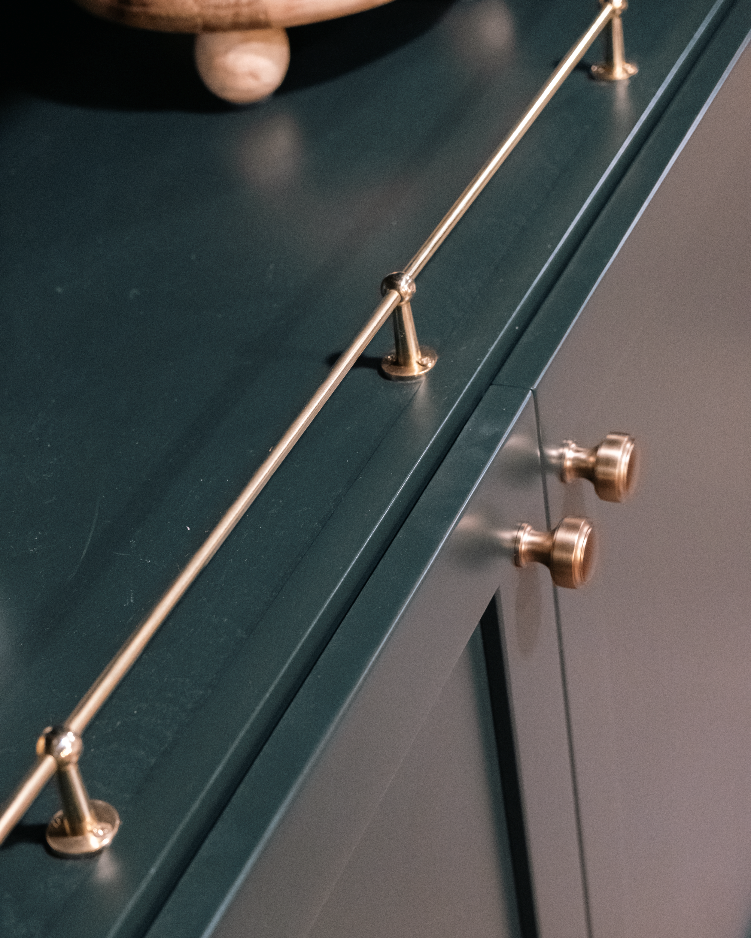 Dark green cabinet with sleek brass rail and knobs, creating a modern, elegant look.