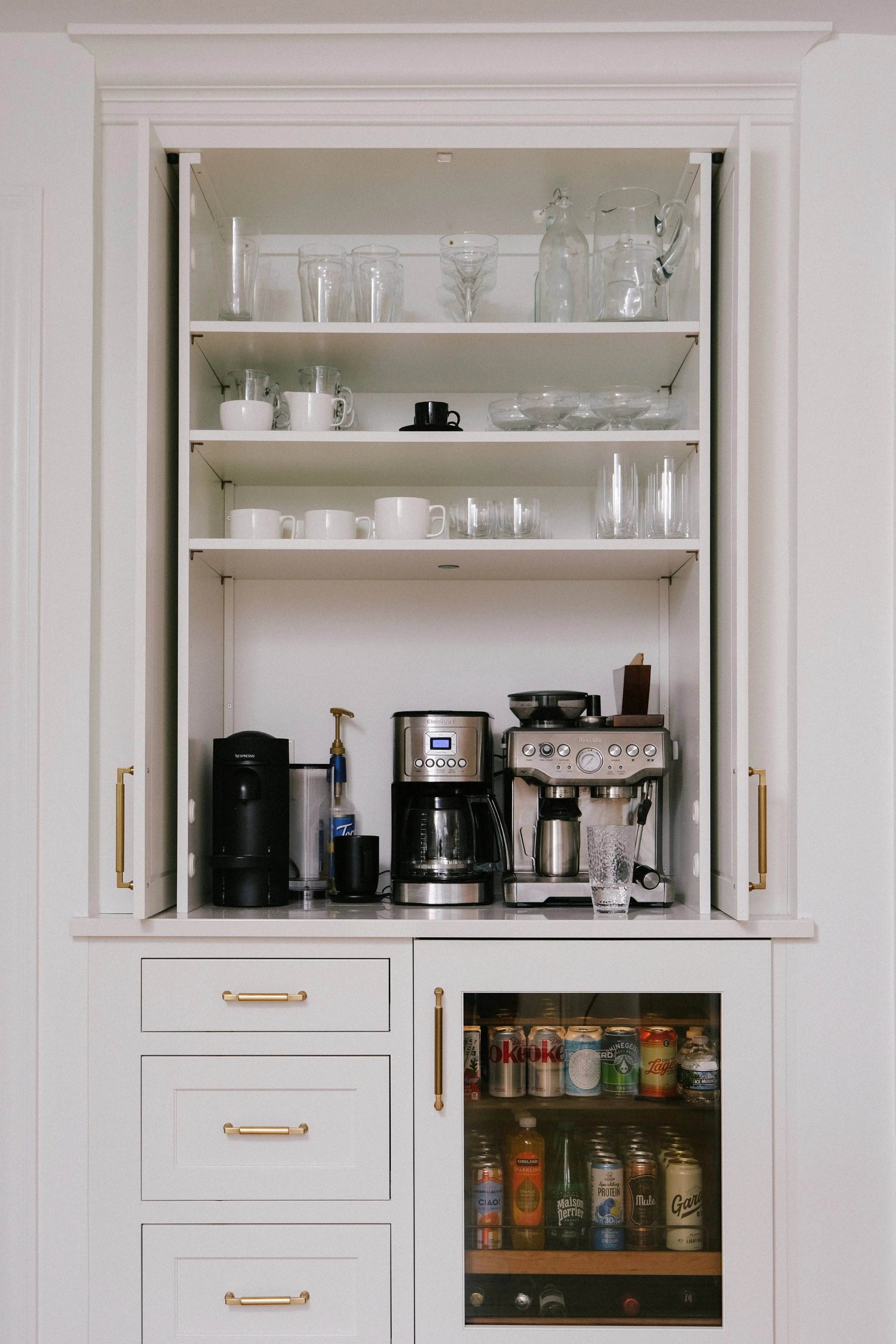 Pocket doors open to reveal an inset coffee bar. A beverage fridge sits below.