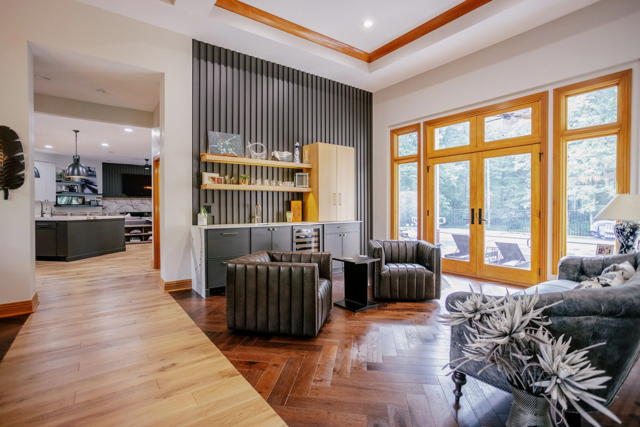 A moody reeded wall overlooks a luxurious sitting room and wet bar. French Oak and White Oak floors line the area.