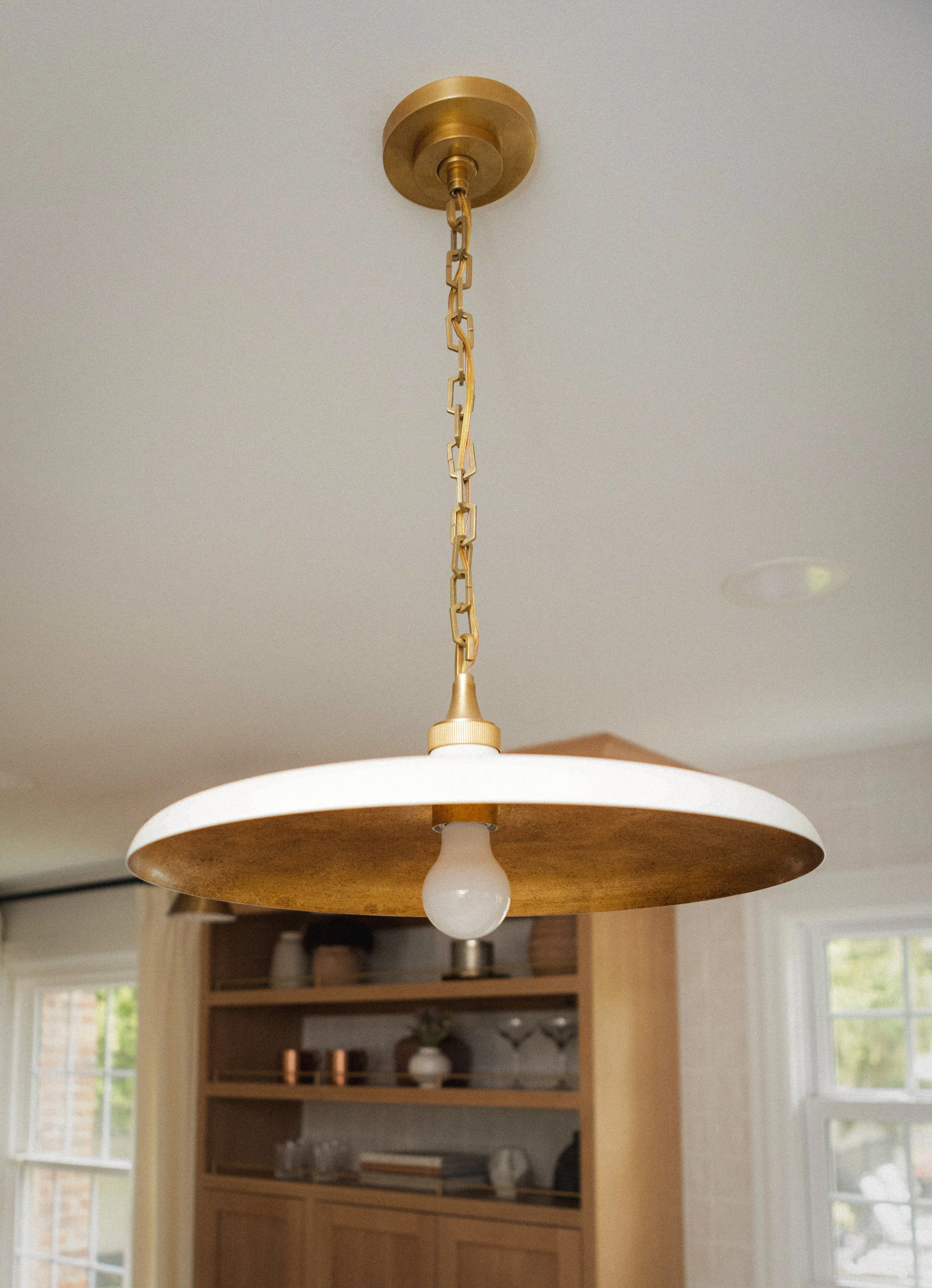 A Visual Comfort Piatto pendant light hangs elegantly from a chain.