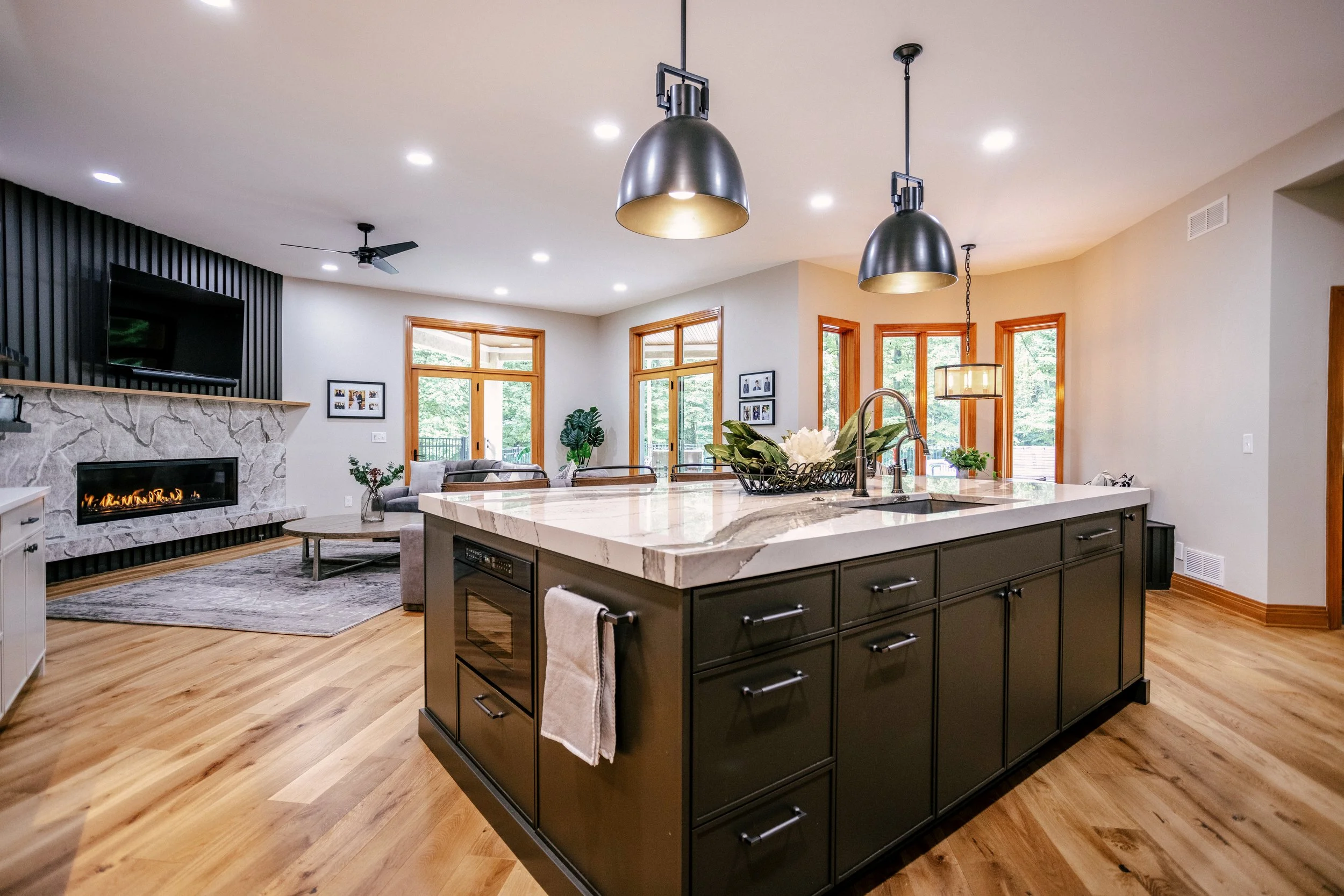 Large ten-foot island topped with Cambria quartz and featuring a drawer microwave sits under pendant lights.