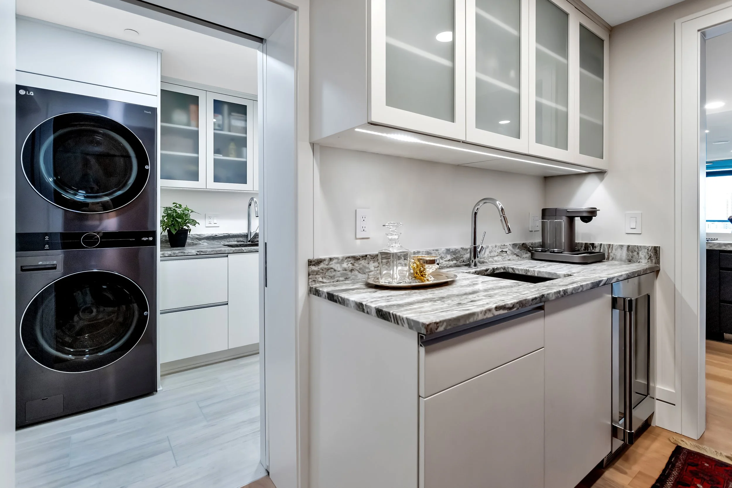 A wet bar with beautiful quartz countertops, contemporary cabinetry, and a coffee maker.