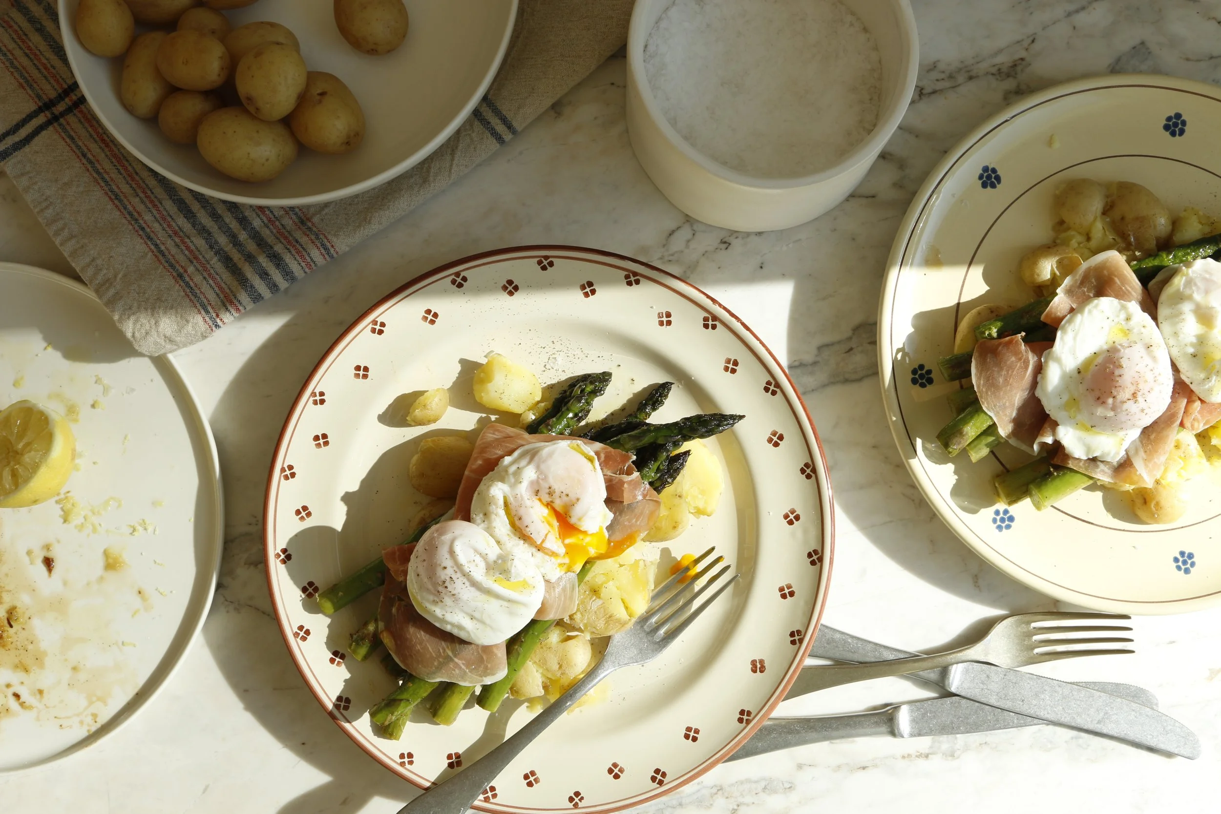 Sliced cucumbers topped with sesame seeds and green onions, served on a decorative plate with white sauce or yogurt.