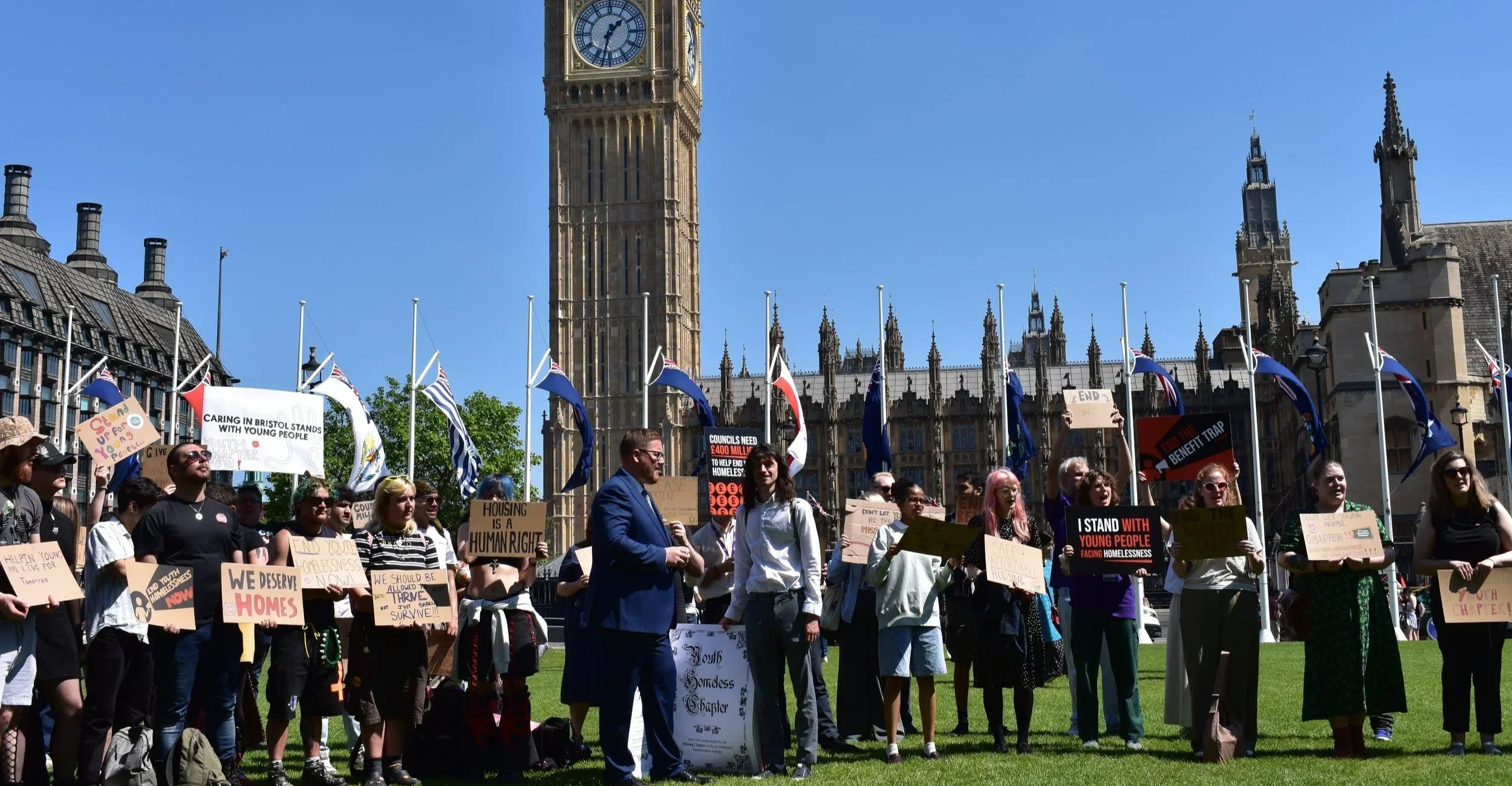A group of campaigners outside parliament holding placards and banners calling to end youth homelessness
