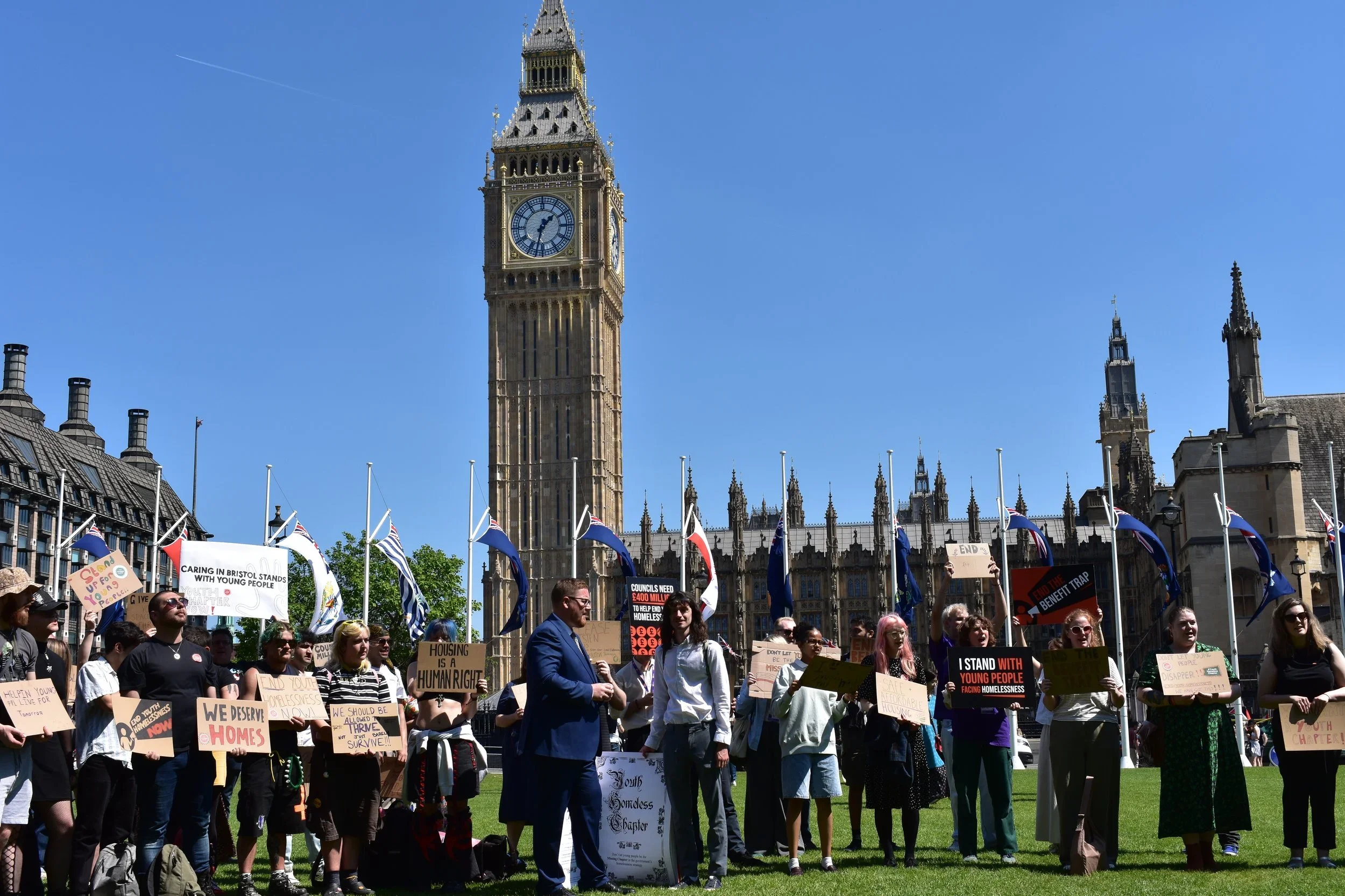  Members of the Youth Homelessness Collective gathering outside Parliament with signs and banners 