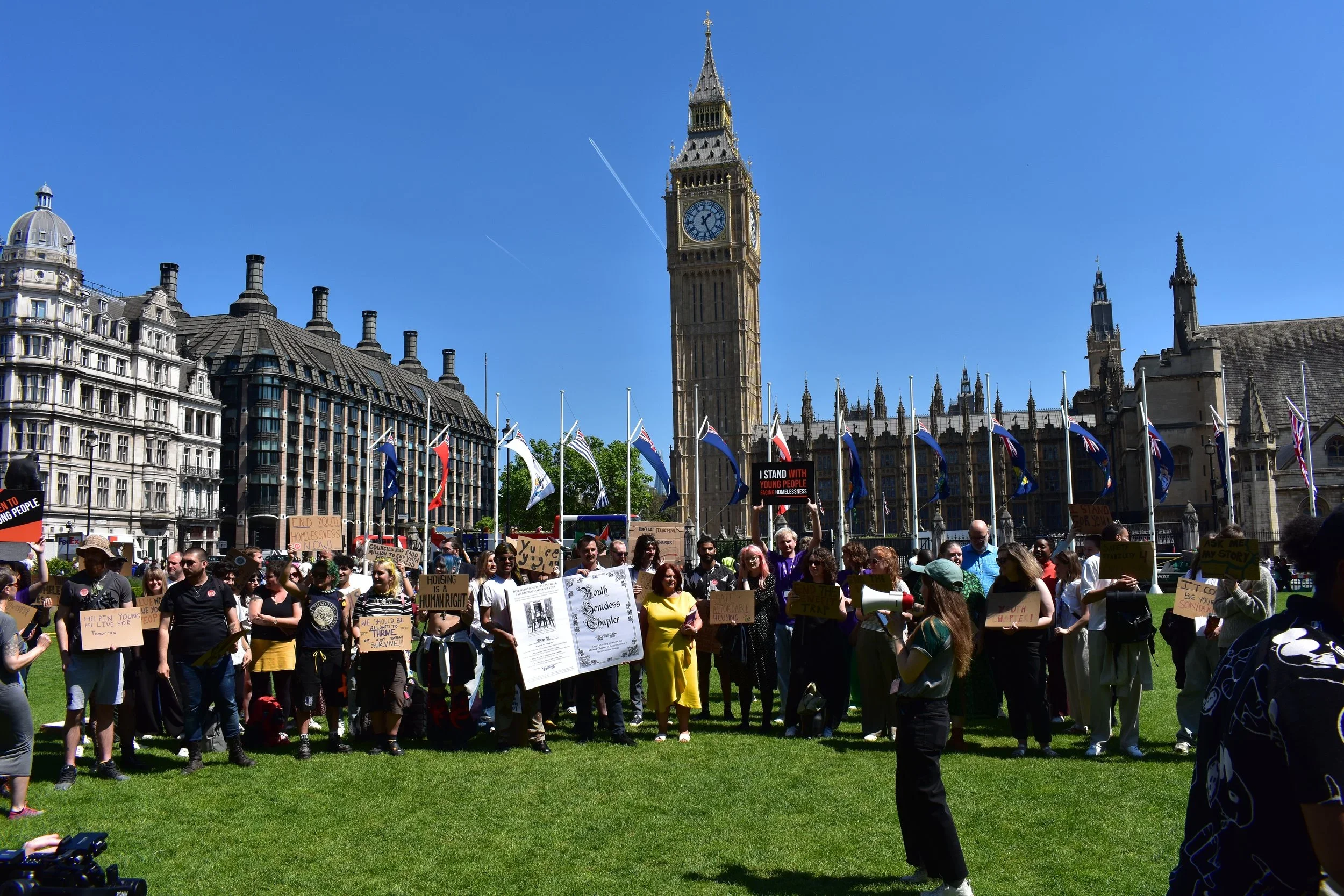  A person with a megaphone addresses the members of the Youth Homelessness Collective gathered outside Parliament 