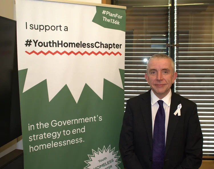 John Grady MP standing in front of a banner in support of the #Planforthe136K