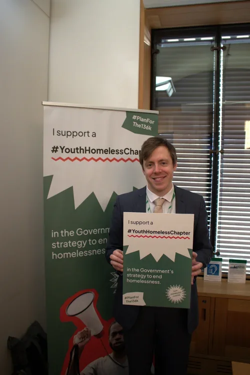James Naish MP holding a sign in support of the #Planforthe136K