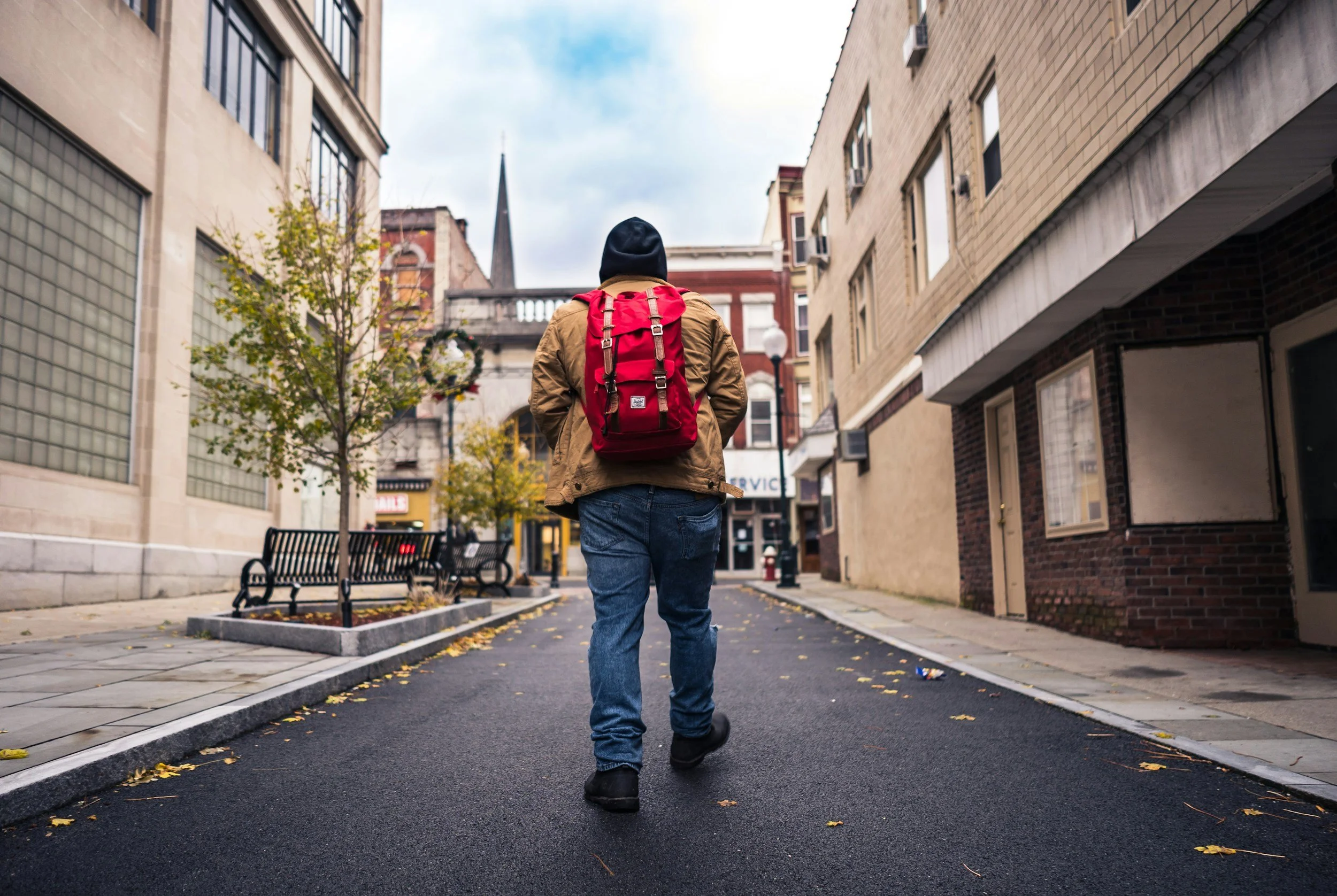 A young person facing away from the camera wearing a red rucksack
