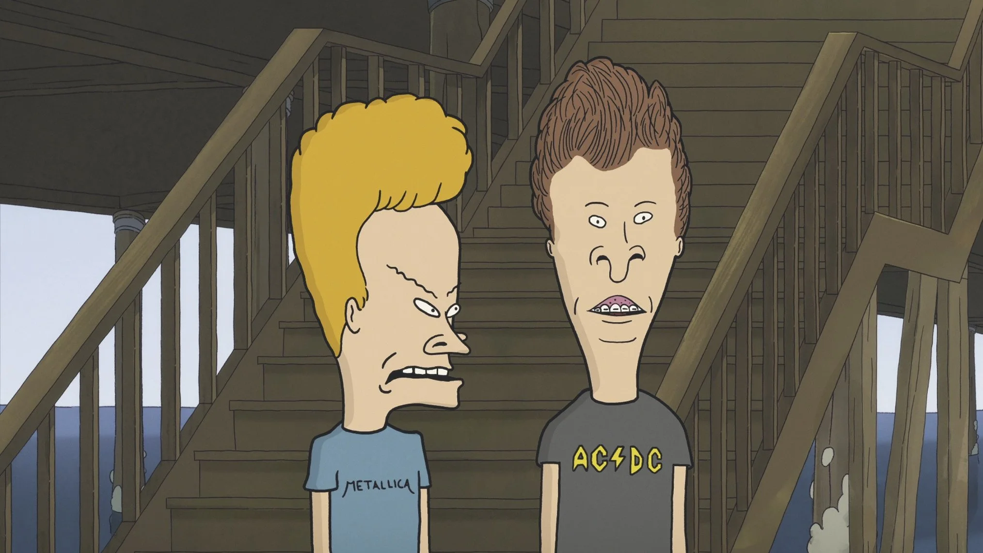 Animated scene of two male characters, Beavis and Butthead, on a wooden dock. One has blond, curly hair and a blue Metallica t-shirt, the other has brown, spiky hair and a black AC/DC t-shirt, both staring at each other with exaggerated expressions.