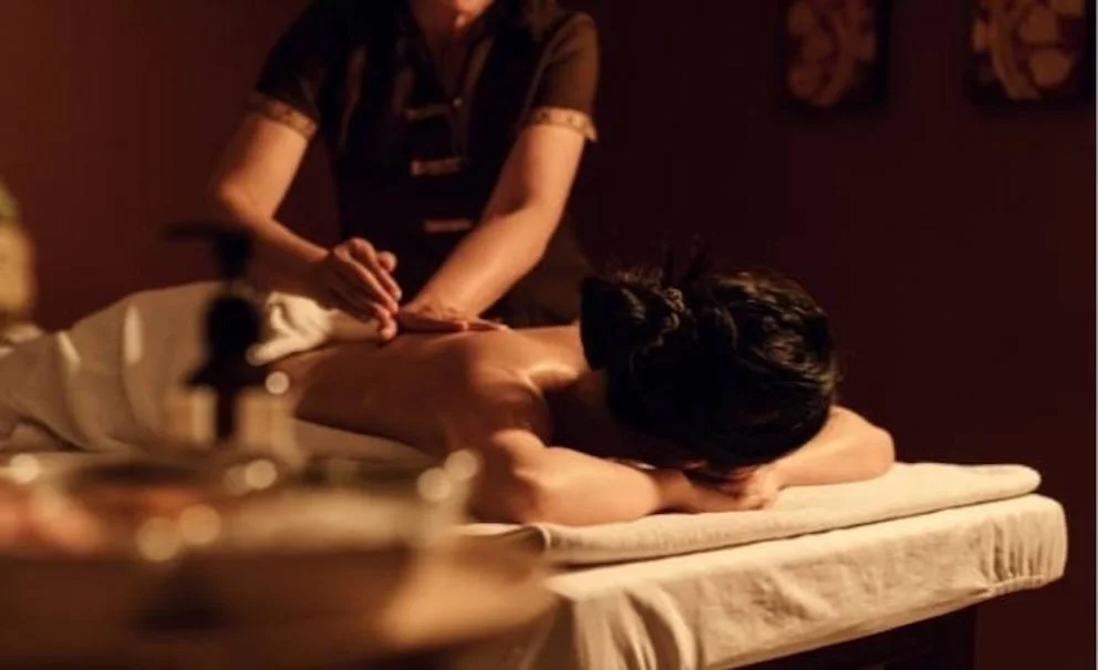 Jemand erhält eine Massage in einer ruhigen, gedämpften Beleuchtung im Wellnessbereich