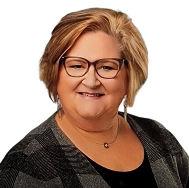 A smiling woman with short, light brown hair, glasses, and wearing a black and gray patterned top.