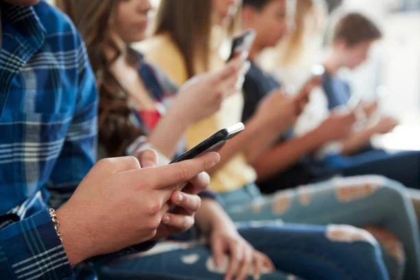Several people sitting in a row using smartphones.