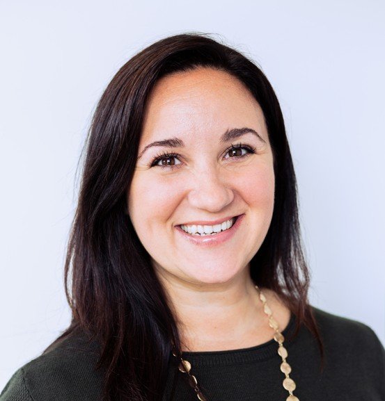 Nicole Lefman, MS - Headshot - Portrait of a woman with long dark hair smiling, wearing a black top and a gold necklace.