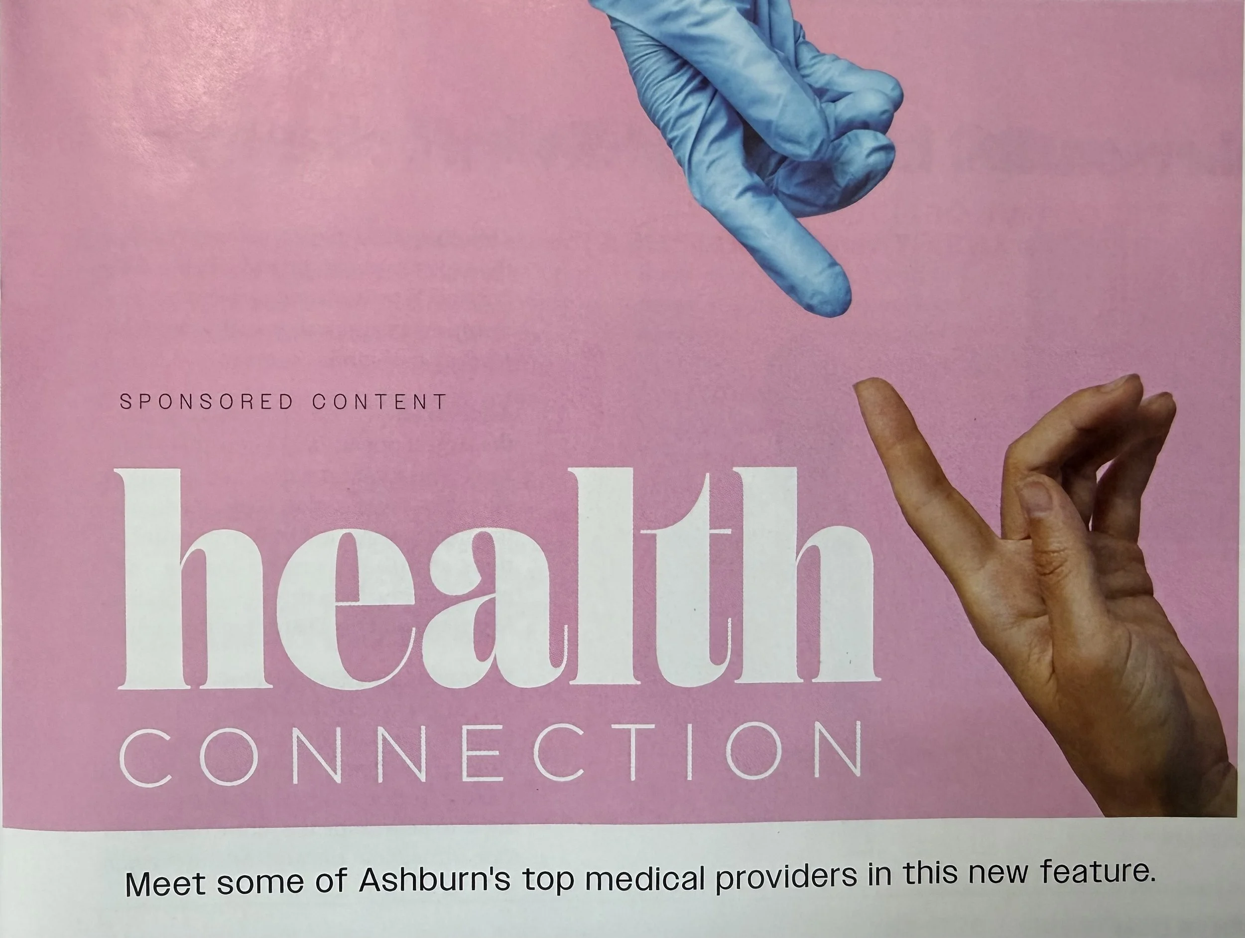 A person of color with short hair holding a pink page with a blue gloved hand pointing at the title. The visible part of the page features large white text that reads 'Health' and smaller white text that says 'Connection'. The bottom of the page has a paragraph of text that begins with 'Meet some of Ashburn's top medical providers in this new feature.'