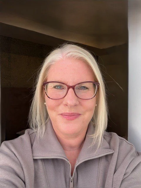 Middle aged woman with glasses and gray quarter zip