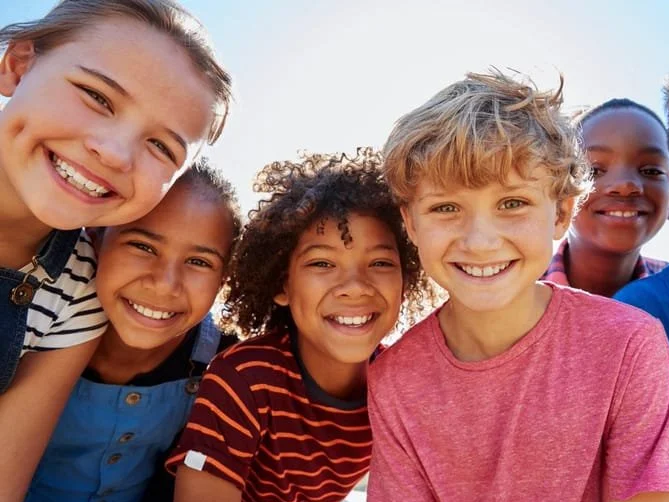 Six children smiling outdoors, close-up group portrait